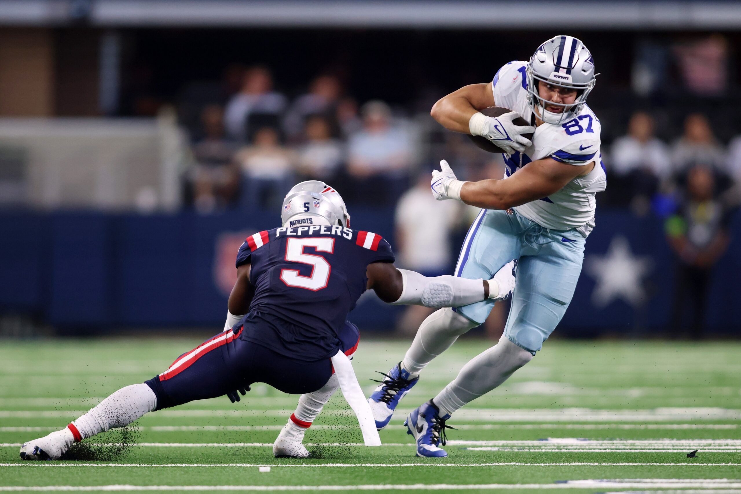 Jake Ferguson (87) attempts to break a tackle of New England Patriots safety Jabrill Peppers (5) in the third quarter at AT&T Stadium.