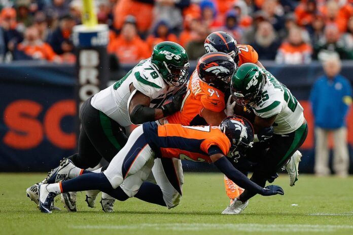 New York Jets running back Ty Johnson (25) is tackled by Denver Broncos defensive end Matt Henningsen (91) and cornerback Damarri Mathis (27) and cornerback K'Waun Williams (21) as New York Jets guard Laken Tomlinson (78) defends in the fourth quarter at Empower Field at Mile High.