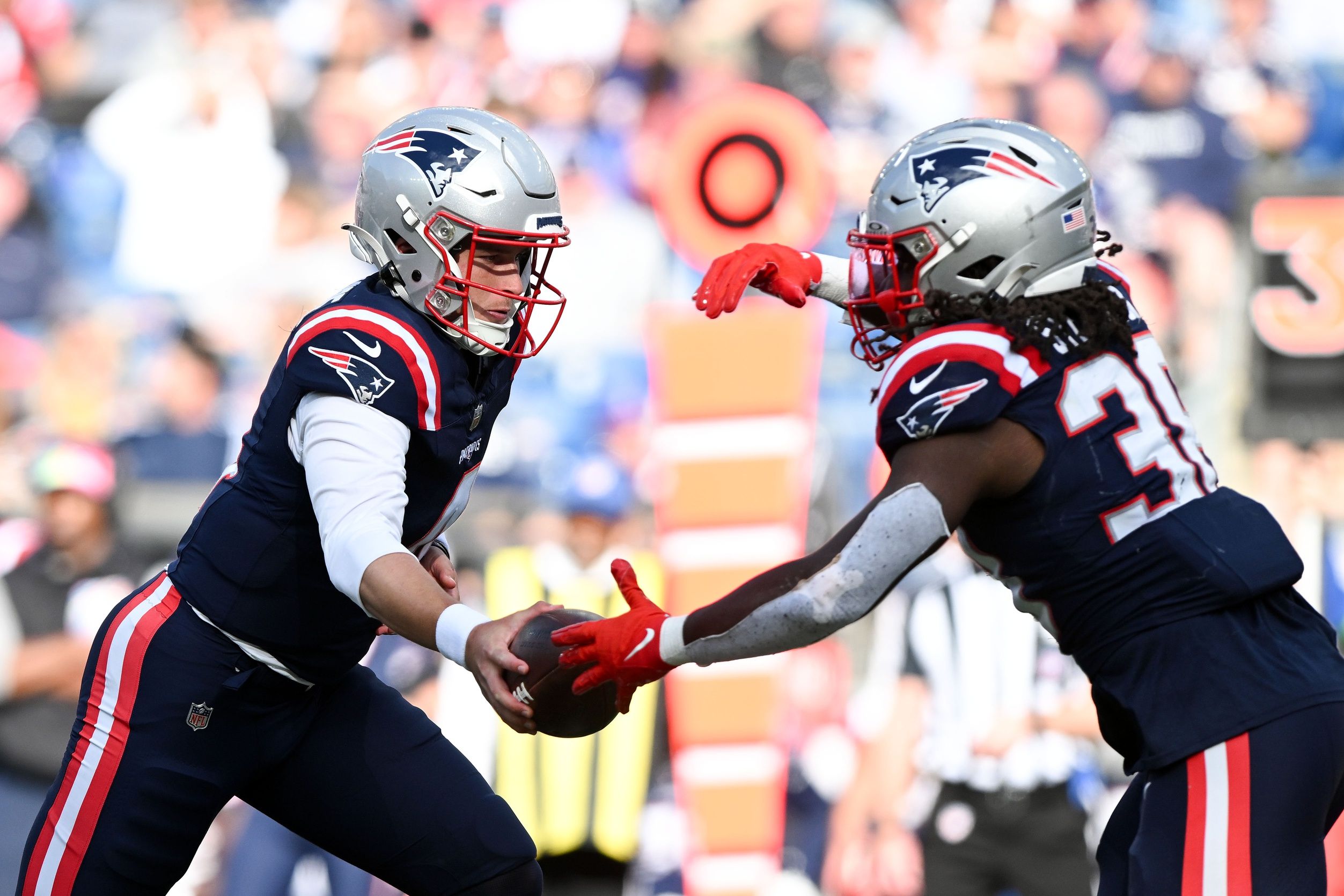 Bailey Zappe (4) hands the ball off to running back Rhamondre Stevenson (38) during the second half of a game against the New Orleans Saints at Gillette Stadium.