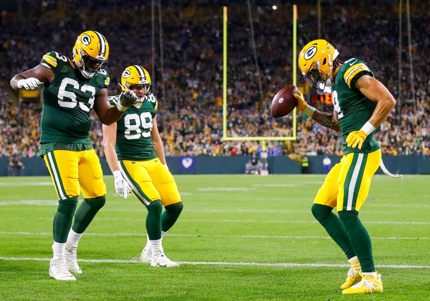 Christian Watson (9) celebrates with offensive tackle Rasheed Walker (63) and tight end Ben Sims (89) after scoring a touchdown.