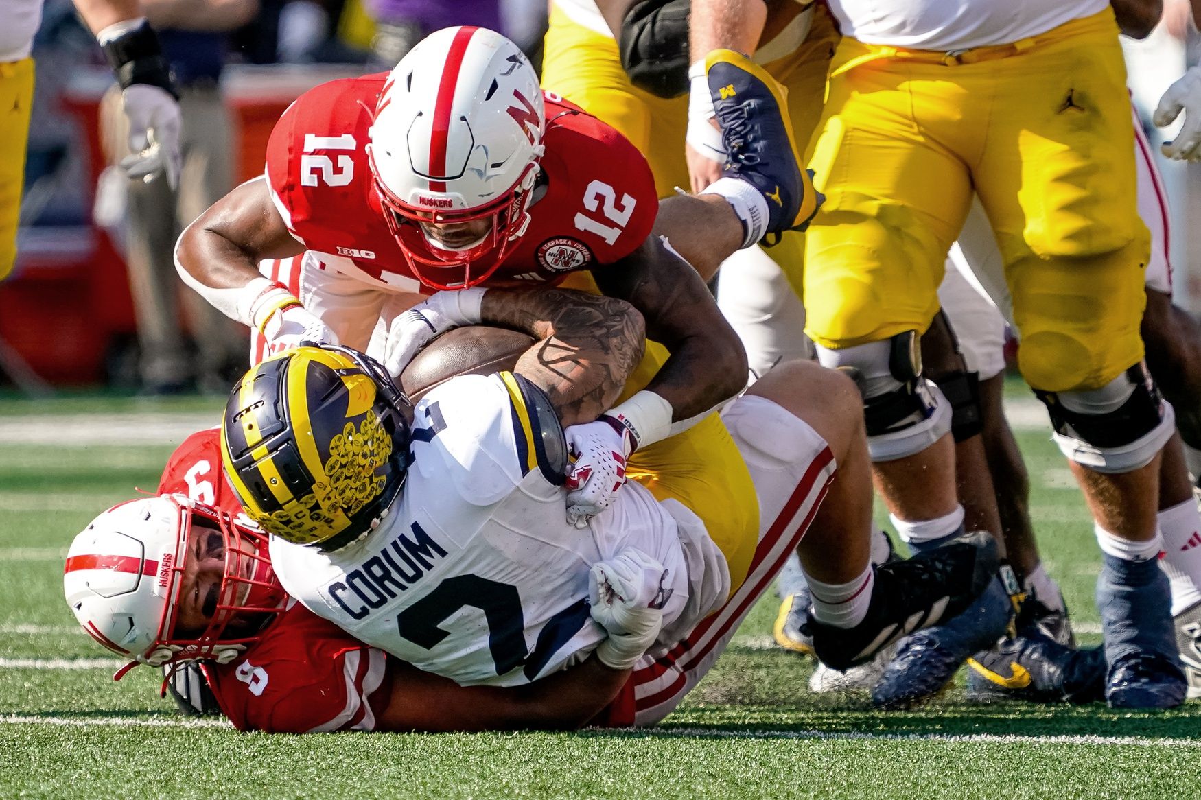 Michigan Wolverines running back Blake Corum (2) is tackled by Nebraska Cornhuskers defensive back Omar Brown (12) and defensive lineman Ty Robinson (9) during the second quarter at Memorial Stadium.