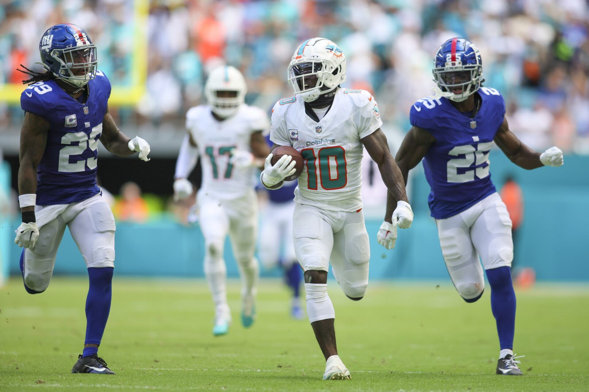 Miami Dolphins wide receiver Tyreek Hill (10) runs with the football ahead of New York Giants cornerback Deonte Banks (25) and safety Xavier McKinney (29).