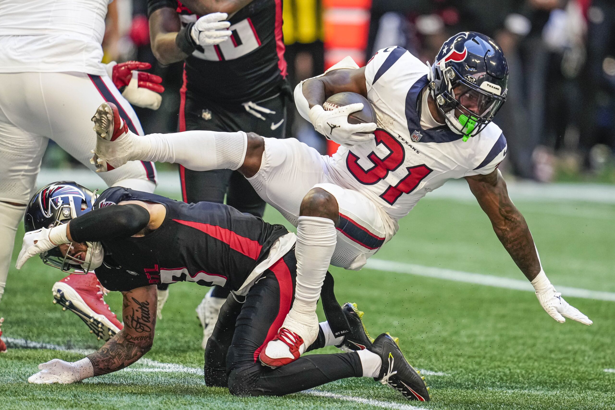 Dameon Pierce (31) gets tripped up by an Atlanta Falcons defender at Mercedes-Benz Stadium.