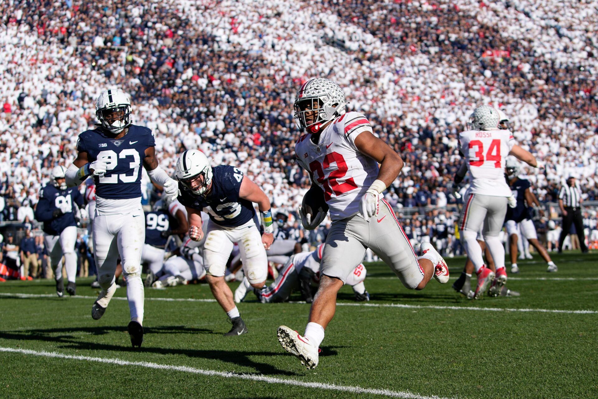 Ohio State Buckeyes running back TreVeyon Henderson (32) runs for a 7-yard touchdown past Penn State Nittany Lions linebacker Tyler Elsdon (43) and linebacker Curtis Jacobs (23) during the fourth quarter of the NCAA Division I football game at Beaver Stadium.