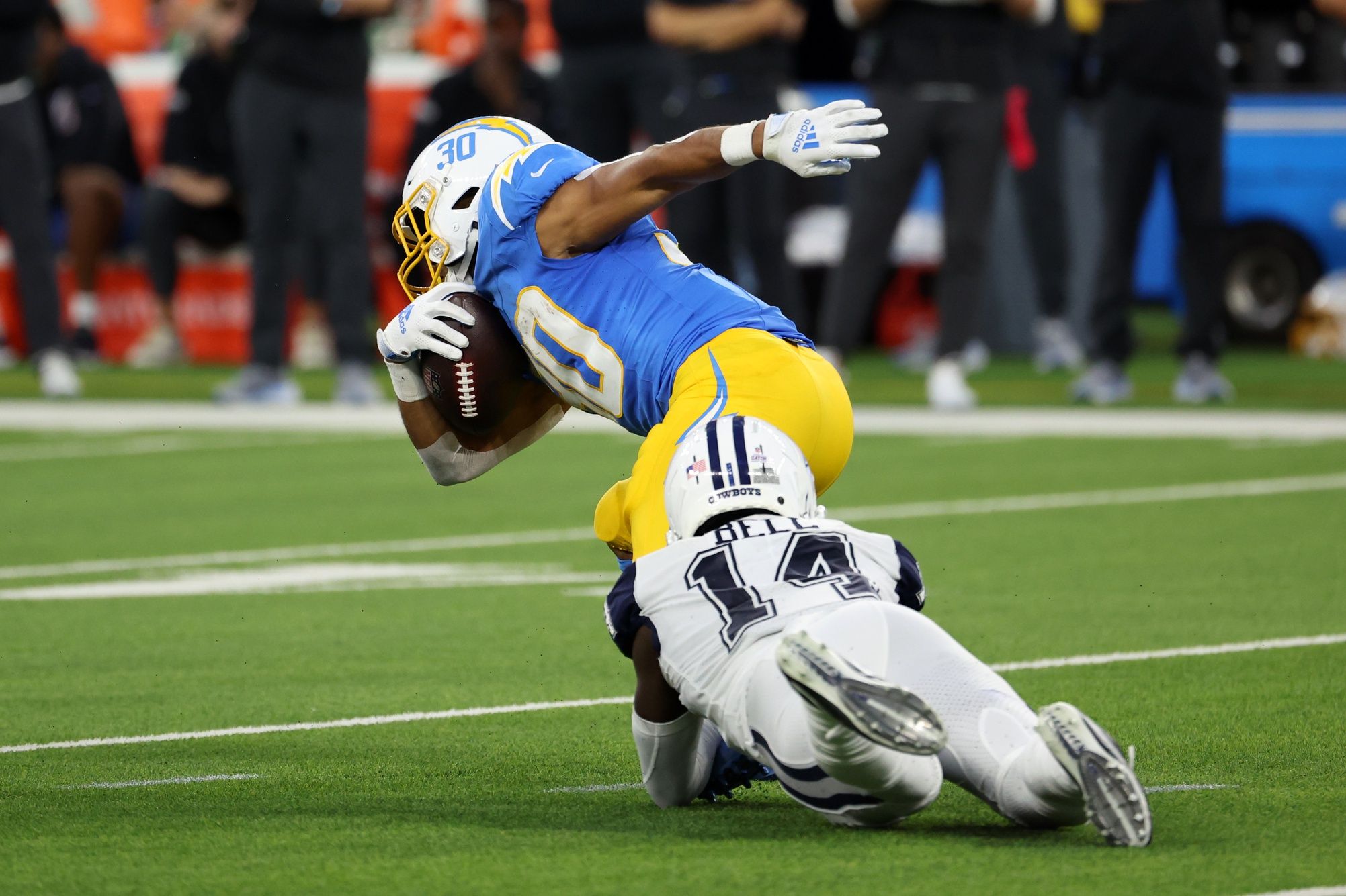 Austin Ekeler (30) is tackled by Dallas Cowboys safety Markquese Bell (14) during the second quarter at SoFi Stadium.