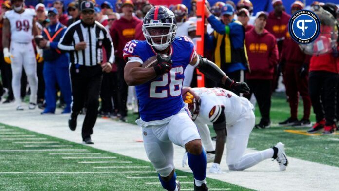 New York Giants running back Saquon Barkley (26) goes up and over Washington Commanders linebacker Jamin Davis (52) to score a first half touchdown at MetLife Stadium.