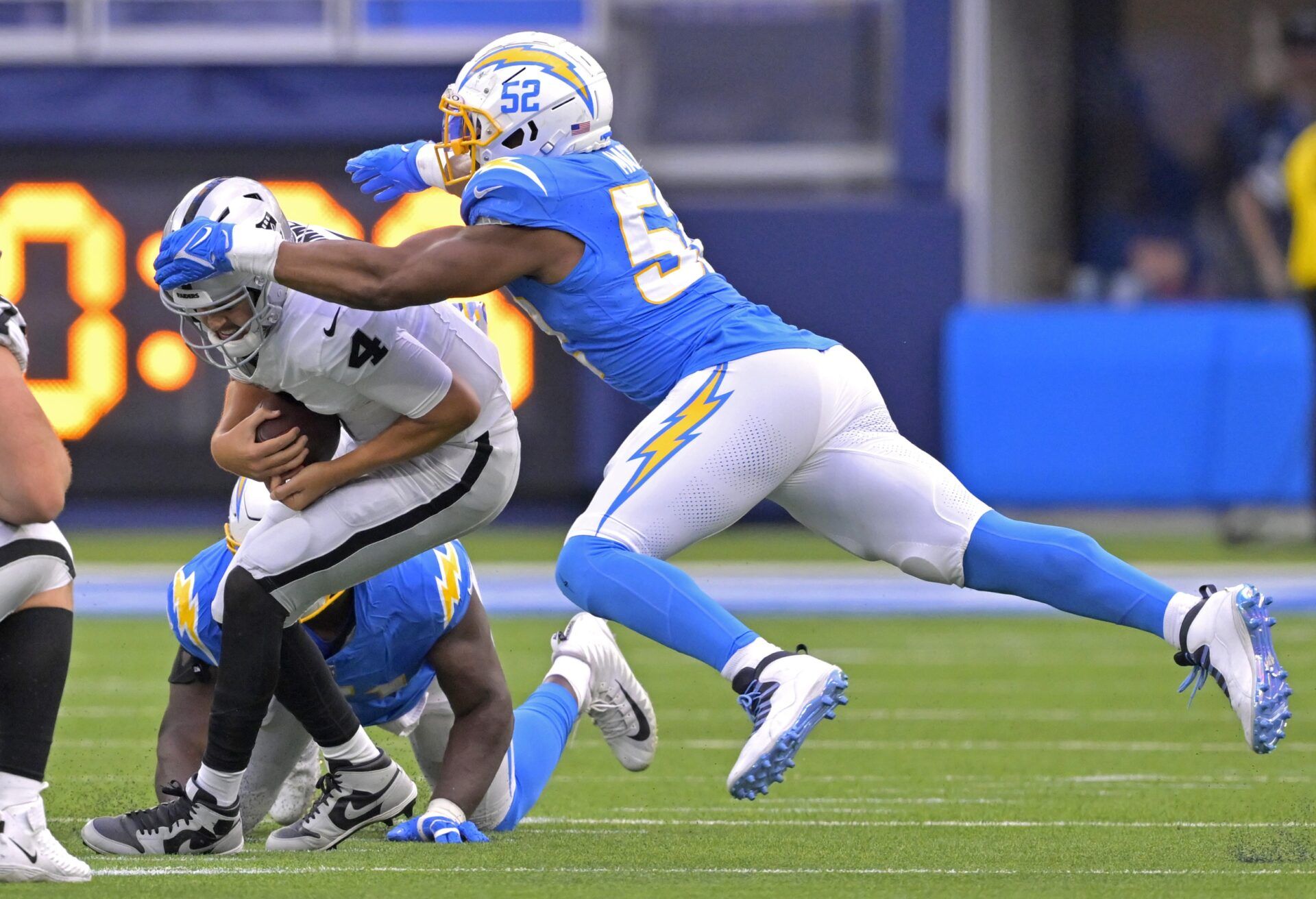 Las Vegas Raiders quarterback Aidan O'Connell (4) escapes the grasp of Los Angeles Chargers defensive tackle Sebastian Joseph-Day (51) but is sacked by linebacker Khalil Mack (52) in the second half at SoFi Stadium.