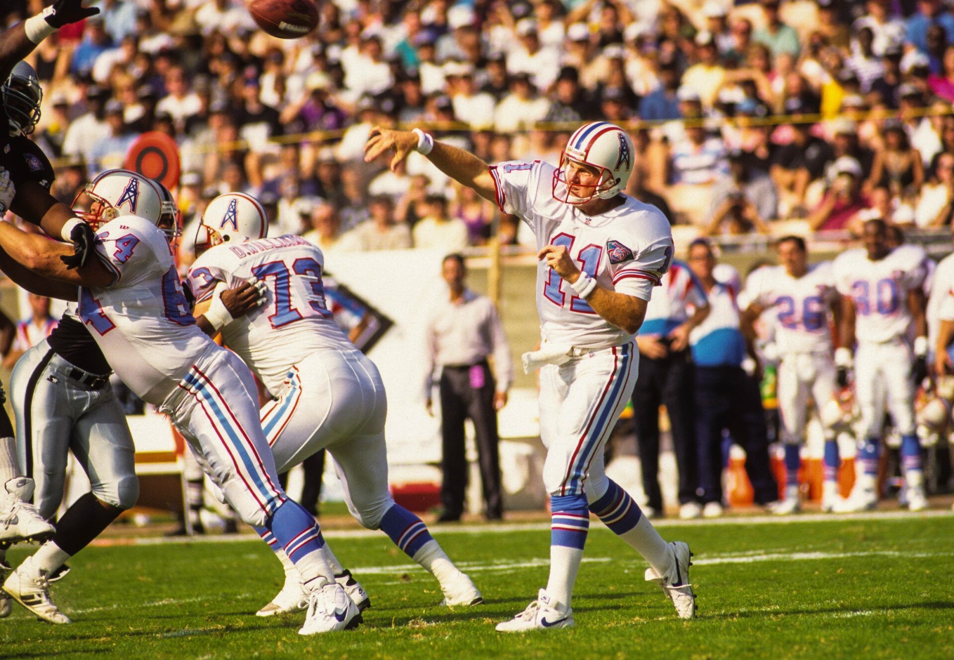 Houston Oilers quarterback Billy Joe Tolliver (11) throws the ball behind Erik Norgard (64) and David Williams (73) against the Los Angeles Raiders at Los Angeles Memorial Coliseum.