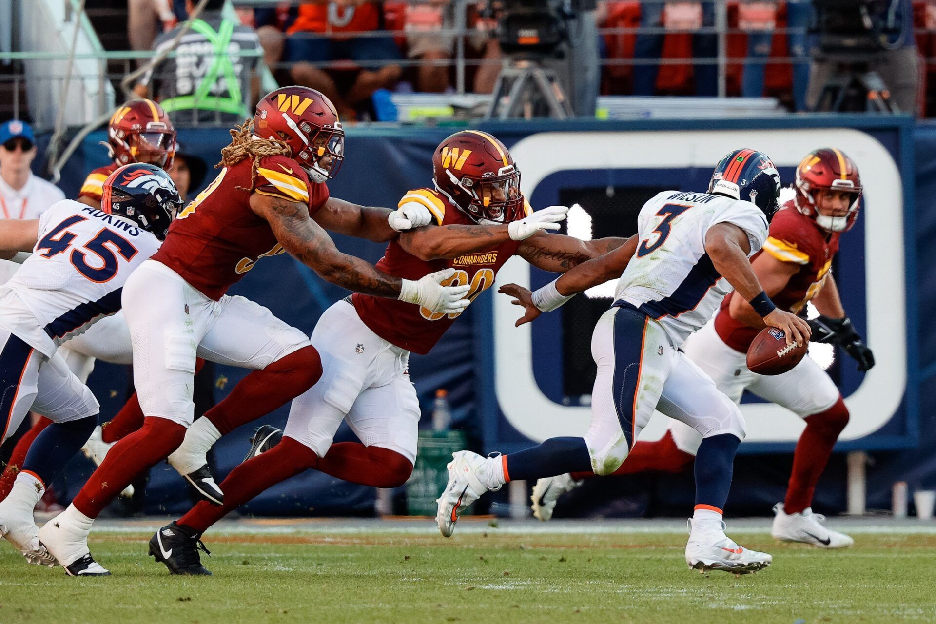 Denver Broncos quarterback Russell Wilson (3) scrambles under pressure from Washington Commanders defensive end Montez Sweat (90) and defensive end Chase Young (99).