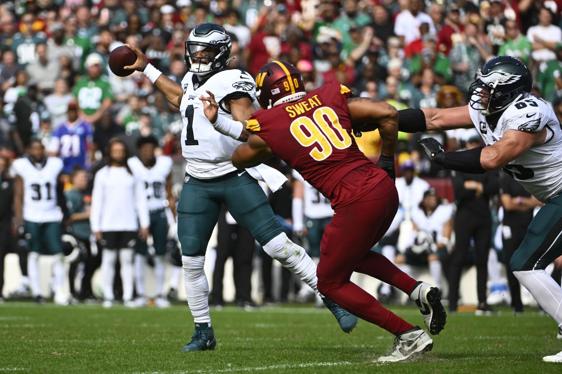 Washington Commanders pass rusher Montez Sweat (90) rushes Philadelphia Eagles QB Jalen Hurts (1).