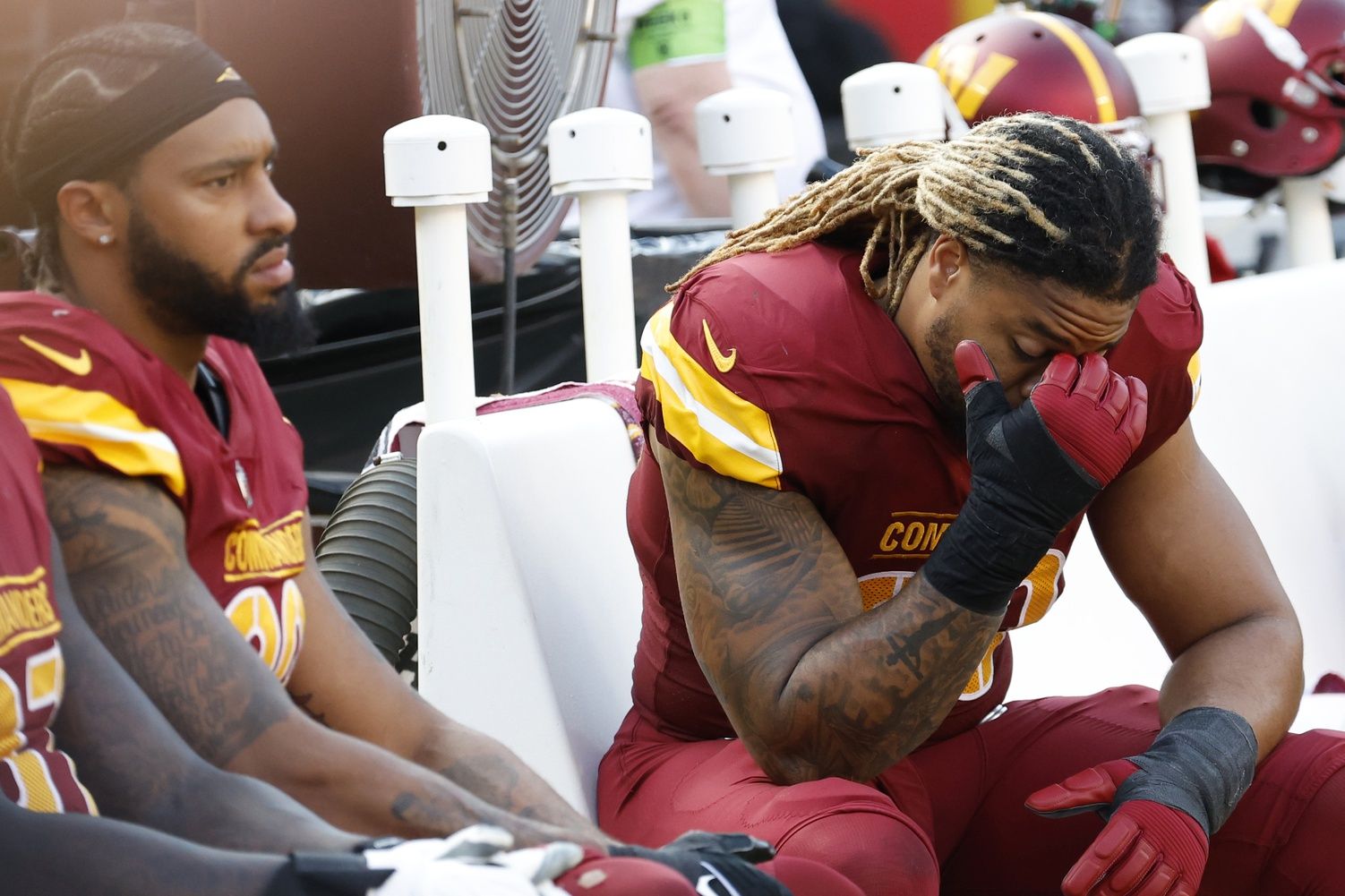 Chase Young sitting on the bench beside Montez Sweat