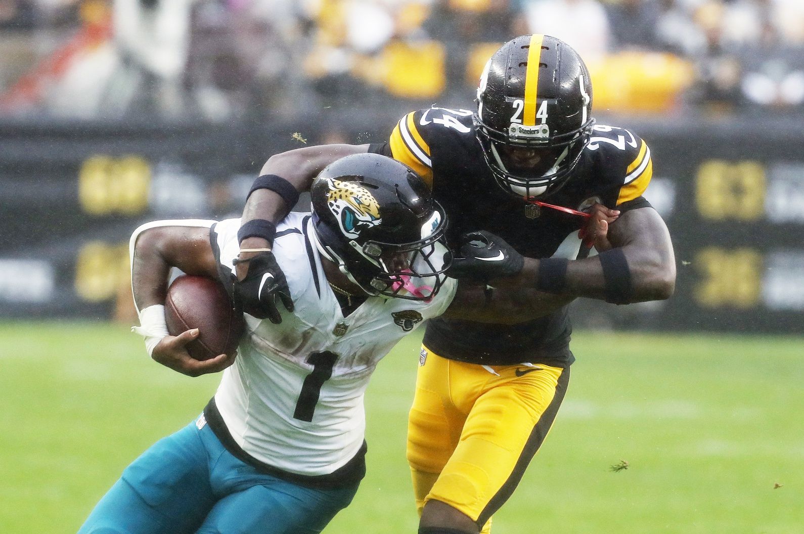 Jacksonville Jaguars running back Travis Etienne Jr. (1) carries the ball as Pittsburgh Steelers cornerback Joey Porter Jr. (24) commits a face-mask penalty.