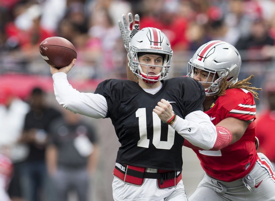 Joe Burrow (10) sends a pass upfield under pressure from Scarlet Team defensive end Chase Young (2) during the Spring Game at Ohio Stadium.