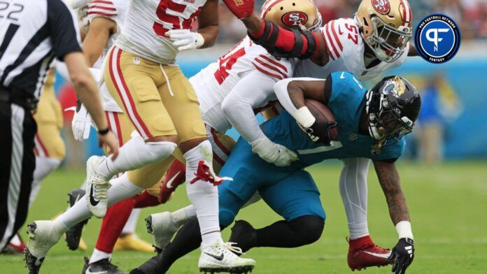 Jacksonville Jaguars running back Travis Etienne Jr. (1) is tackled by San Francisco 49ers linebacker Dre Greenlaw (57) and defensive end Clelin Ferrell (94) during the first quarter of an NFL football game Sunday, Nov. 12, 2023 at EverBank Stadium in Jacksonville, Fla.