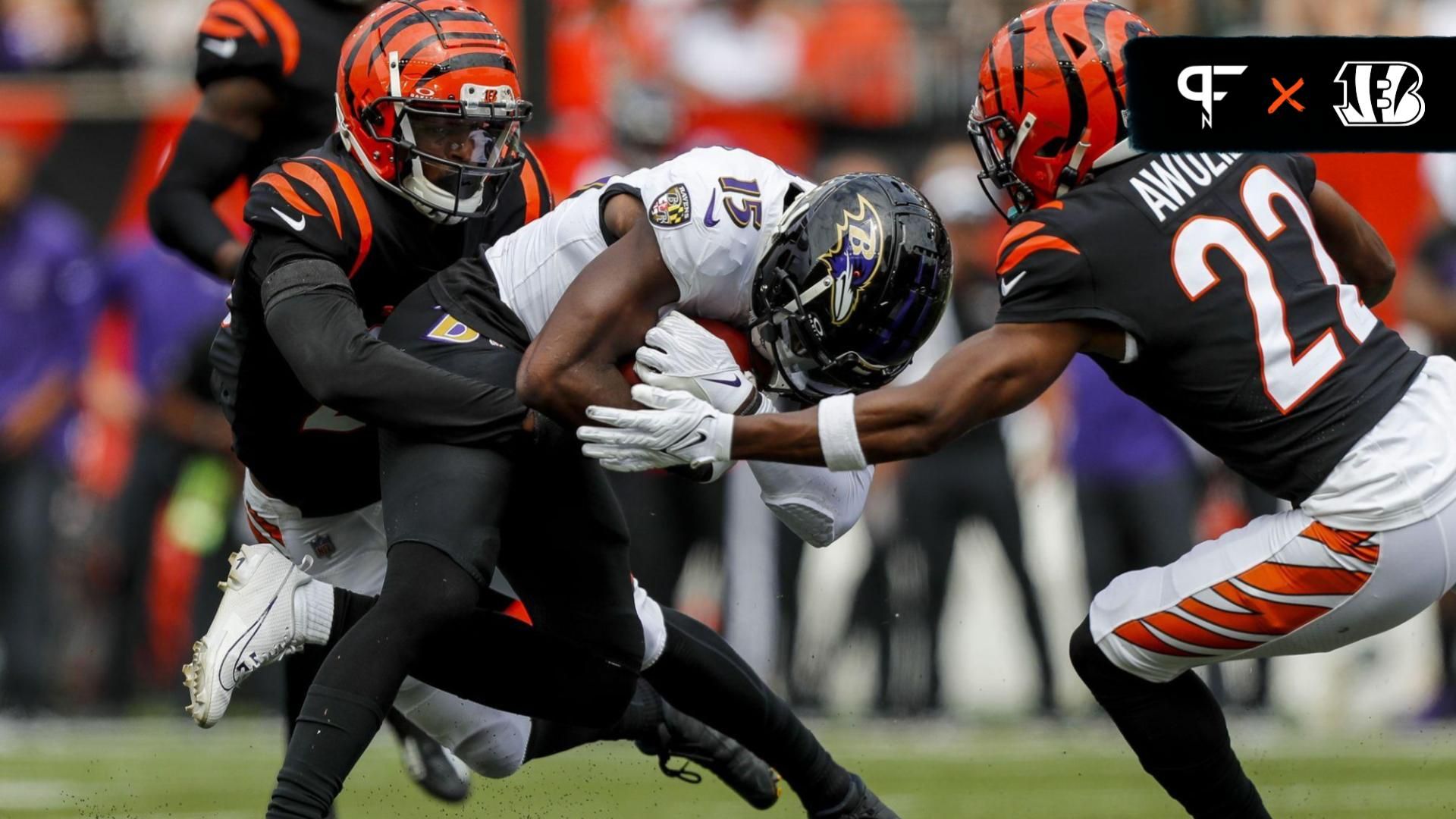 Cincinnati Bengals safety Dax Hill (23) and cornerback Chidobe Awuzie (22) bring down Baltimore Ravens wide receiver Nelson Agholor (15).