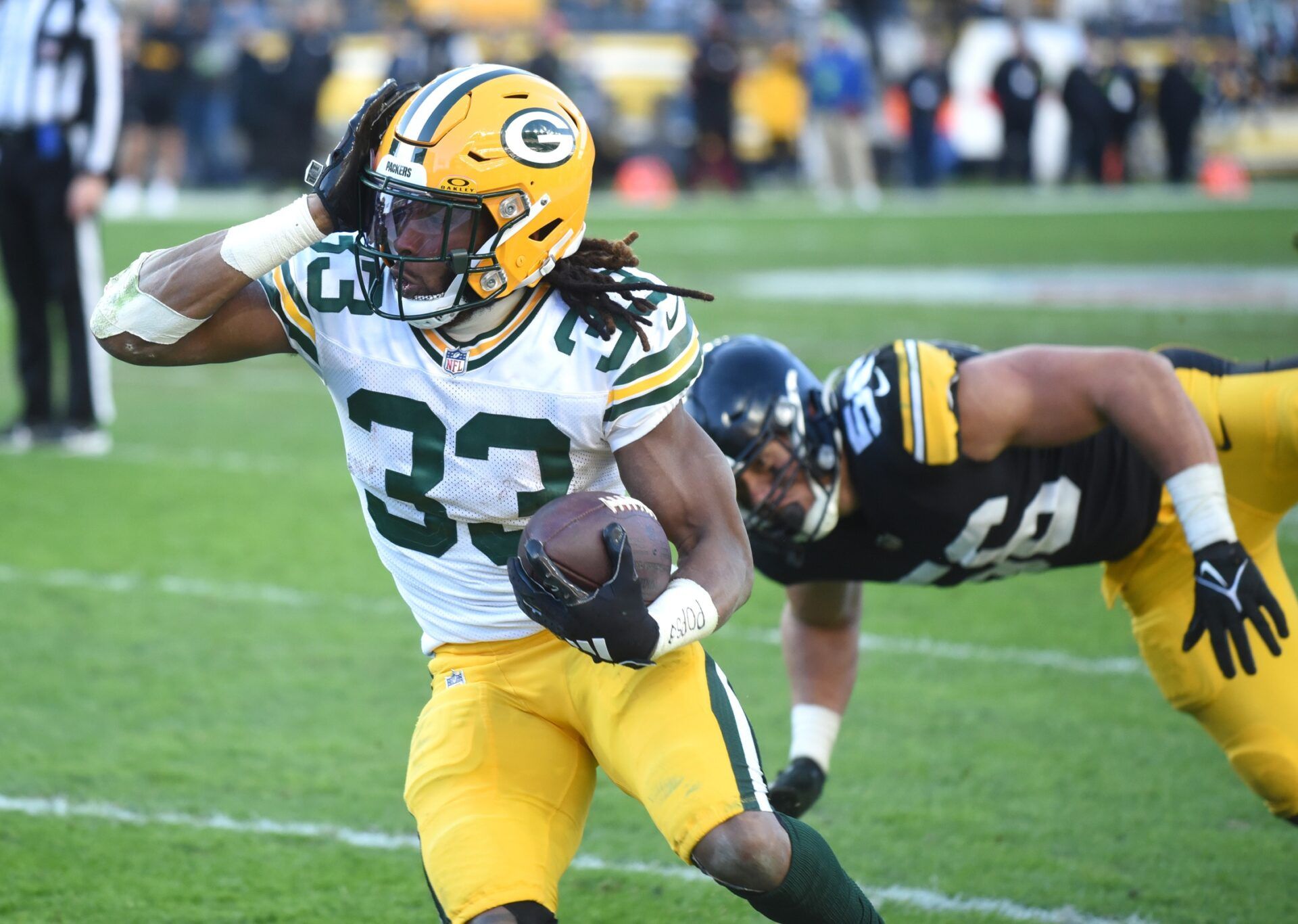 Aaron Jones (33) is chased out of bounds by Pittsburgh Steelers linebacker Alex Highsmith (56) during the fourth quarter at Acrisure Stadium.