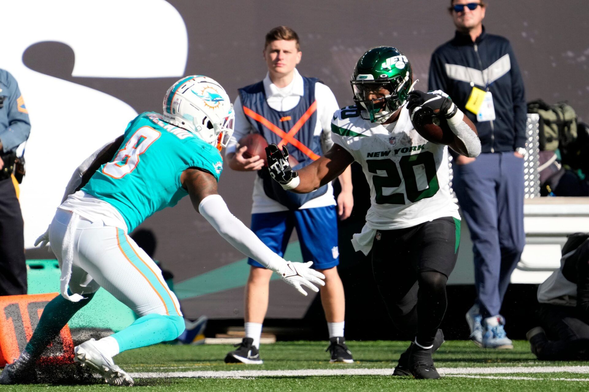 Jets running back Breece Hall (20) runs with the ball as Dolphins free safety Jevon Holland (8) plays defense.