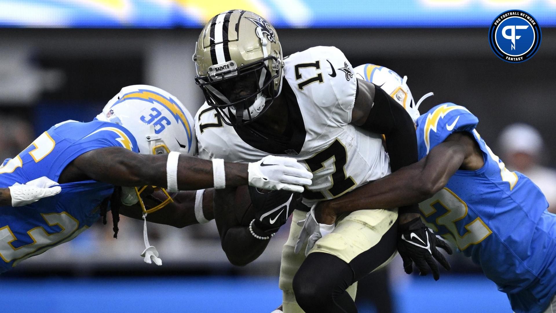 A.T. Perry (17) is tackled by Los Angeles Chargers cornerback Ja'Sir Taylor (36) and safety JT Woods (22) during the first half at SoFi Stadium.