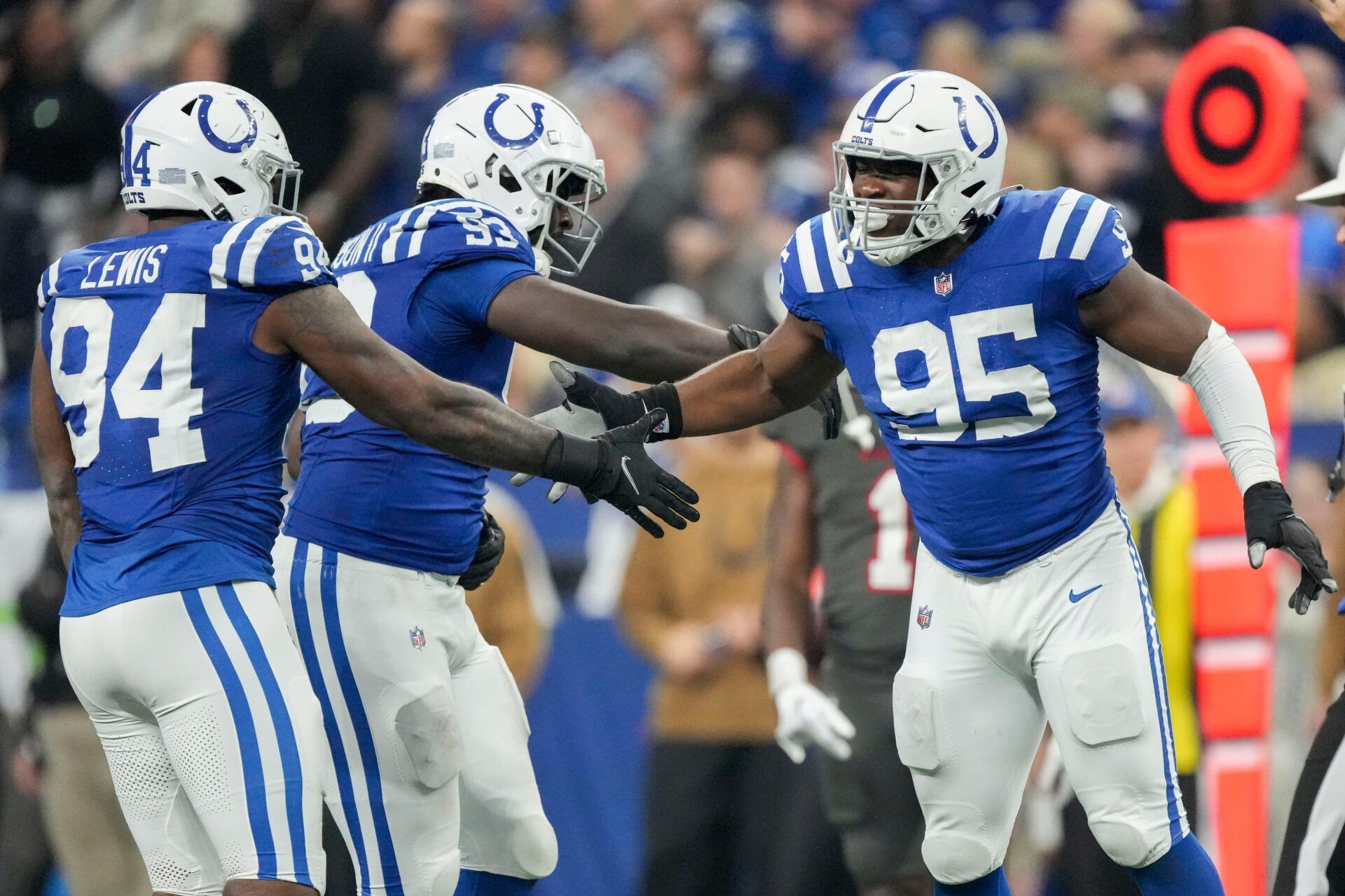 Indianapolis Colts DEs Tyquan Lewis (94) and Adetomiwa Adebawore (95) and DT Eric Johnson II (93) celebrate a sack against the Tampa Bay Buccaneers.