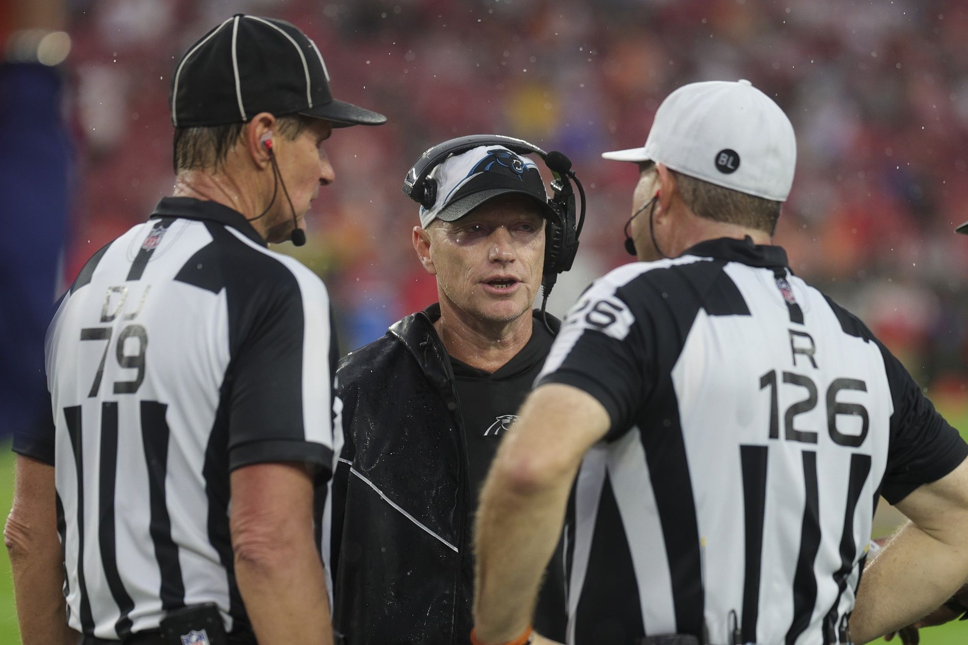 Carolina Panthers interim head coach Chris Taylor speaks to referee Brad Rogers (126) and down judge Kent Payne (79) in the second quarter at Raymond James Stadium.