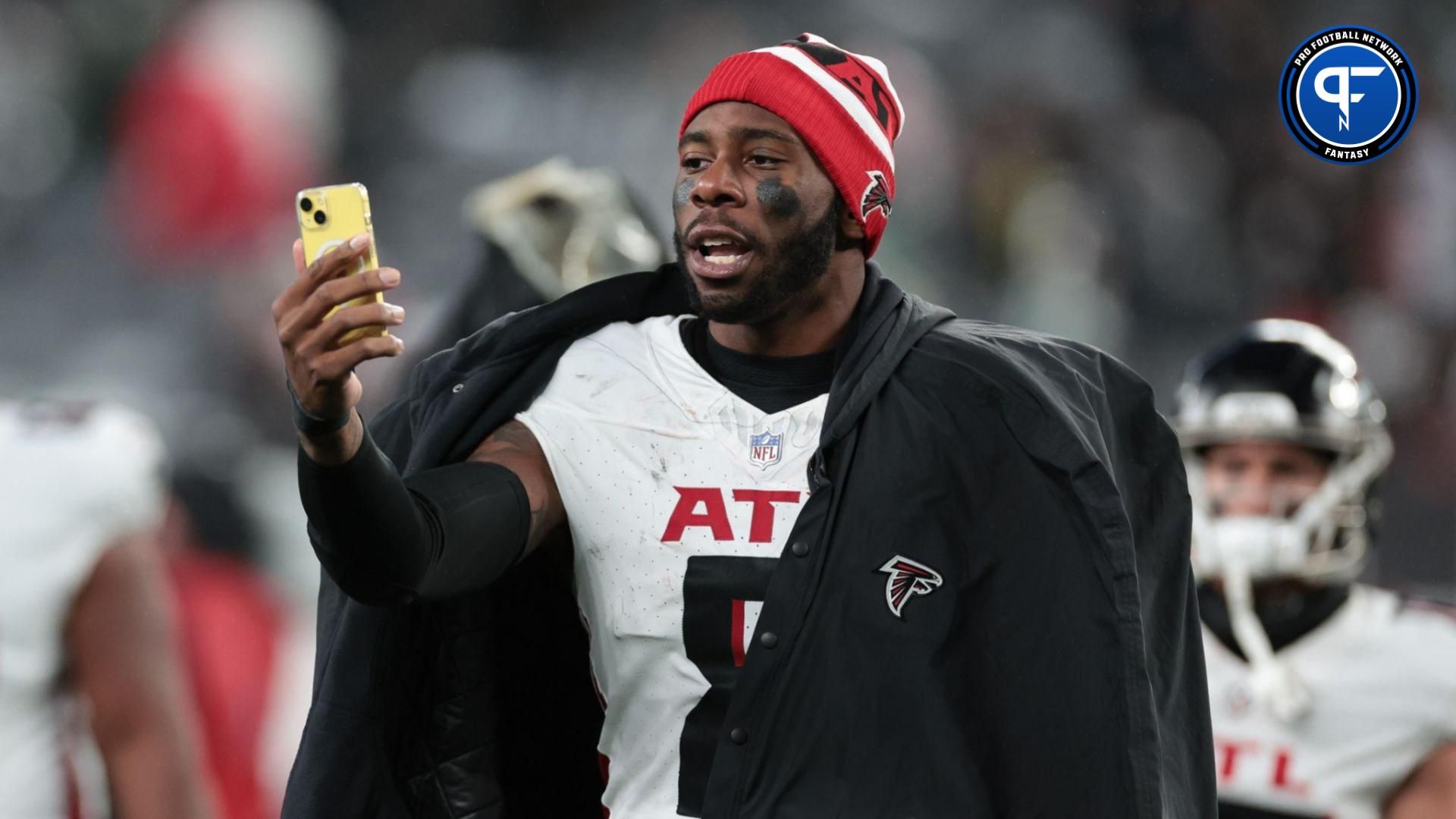 Atlanta Falcons tight end Kyle Pitts (8) addresses social media on a smart phone while walking off the field after the game against the New York Jets at MetLife Stadium.