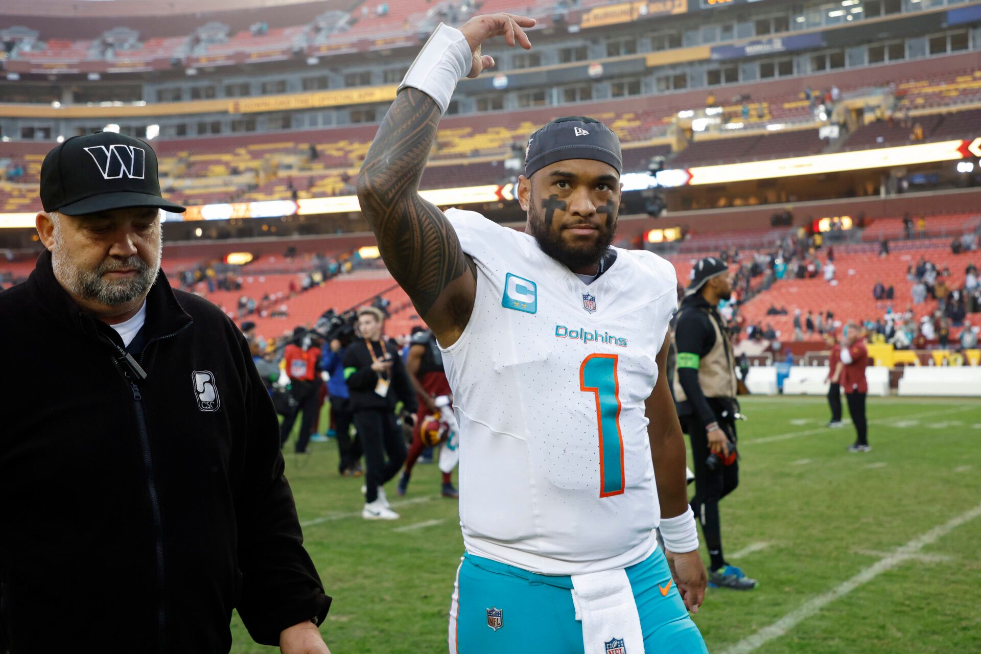 Miami Dolphins quarterback Tua Tagovailoa (1) waves to fans while leaving the field after the Dolphins' game against the Washington Commanders at FedExField.