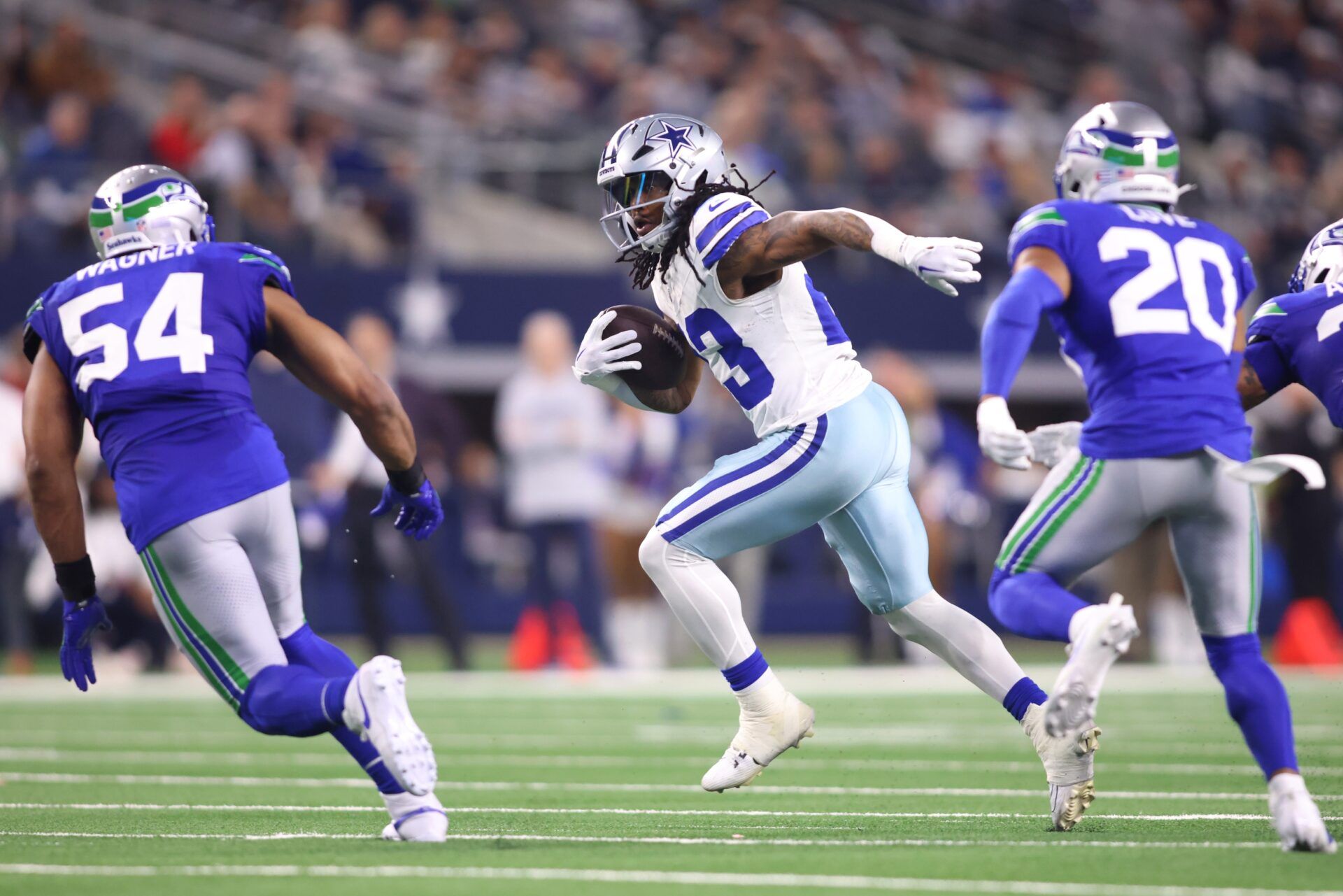 Dallas Cowboys running back Rico Dowdle (23) runs the ball while defended by Seattle Seahawks linebacker Bobby Wagner (54) and safety Julian Love (20) during the first half at AT&T Stadium.