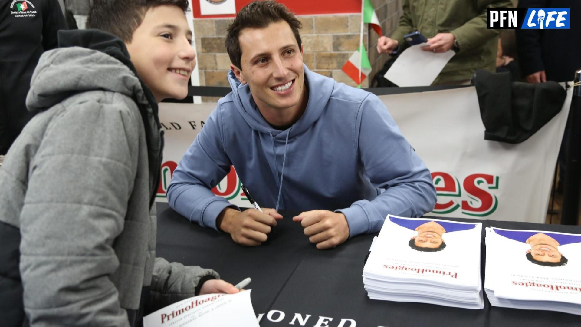 New York Giants QB Tommy DeVito takes a picture with a fan while signing autographs.