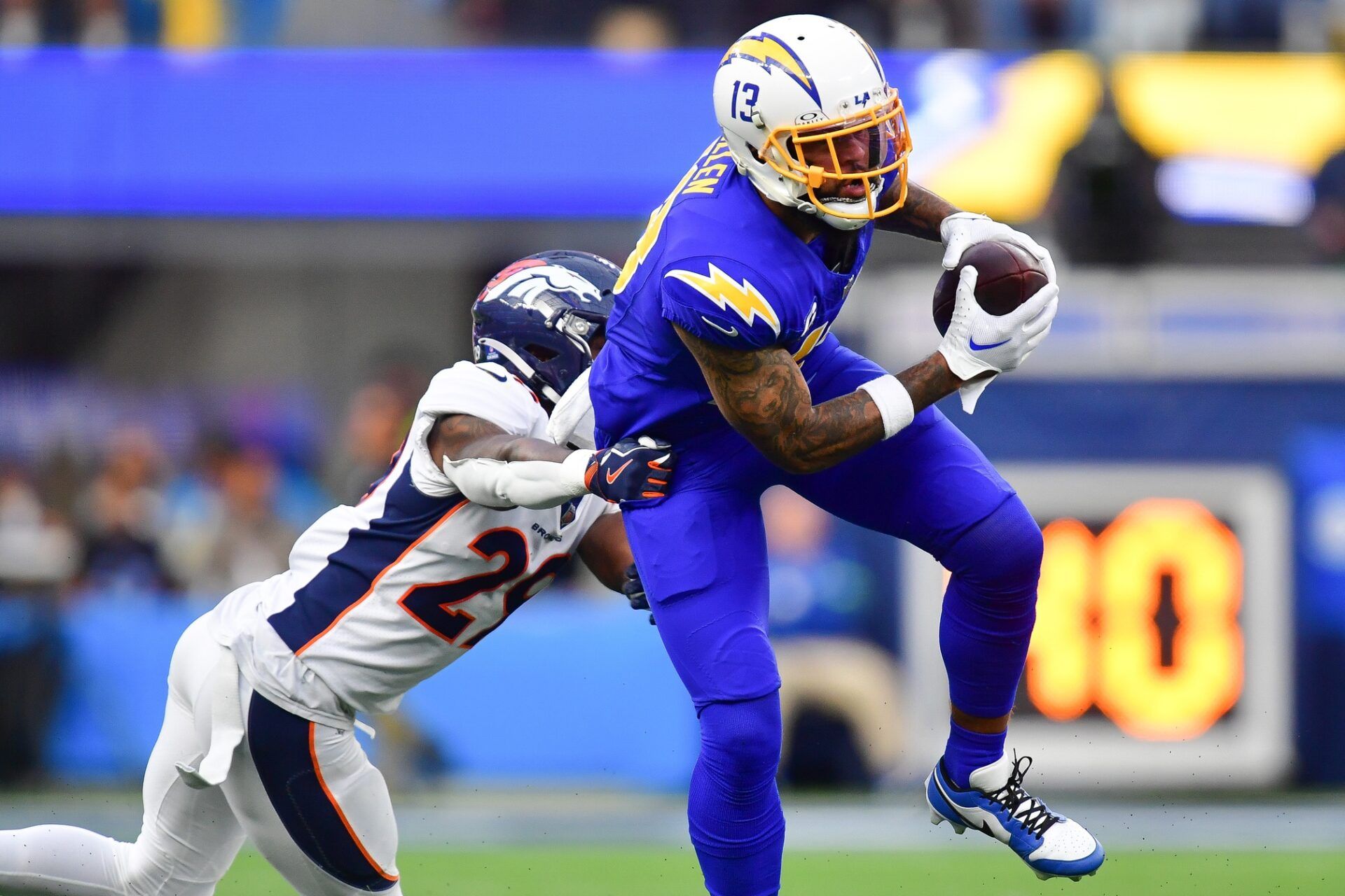 Los Angeles Chargers wide receiver Keenan Allen (13) runs the ball ahead of Denver Broncos cornerback Ja'Quan McMillian (29) during the first half at SoFi Stadium.