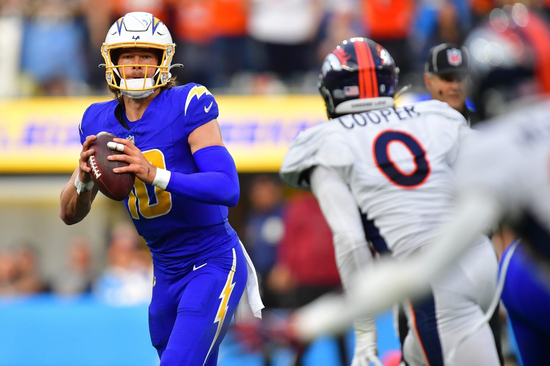 Los Angeles Chargers quarterback Justin Herbert (10) moves out to pass against the defense of Denver Broncos linebacker Jonathon Cooper (0) during the first half at SoFi Stadium.