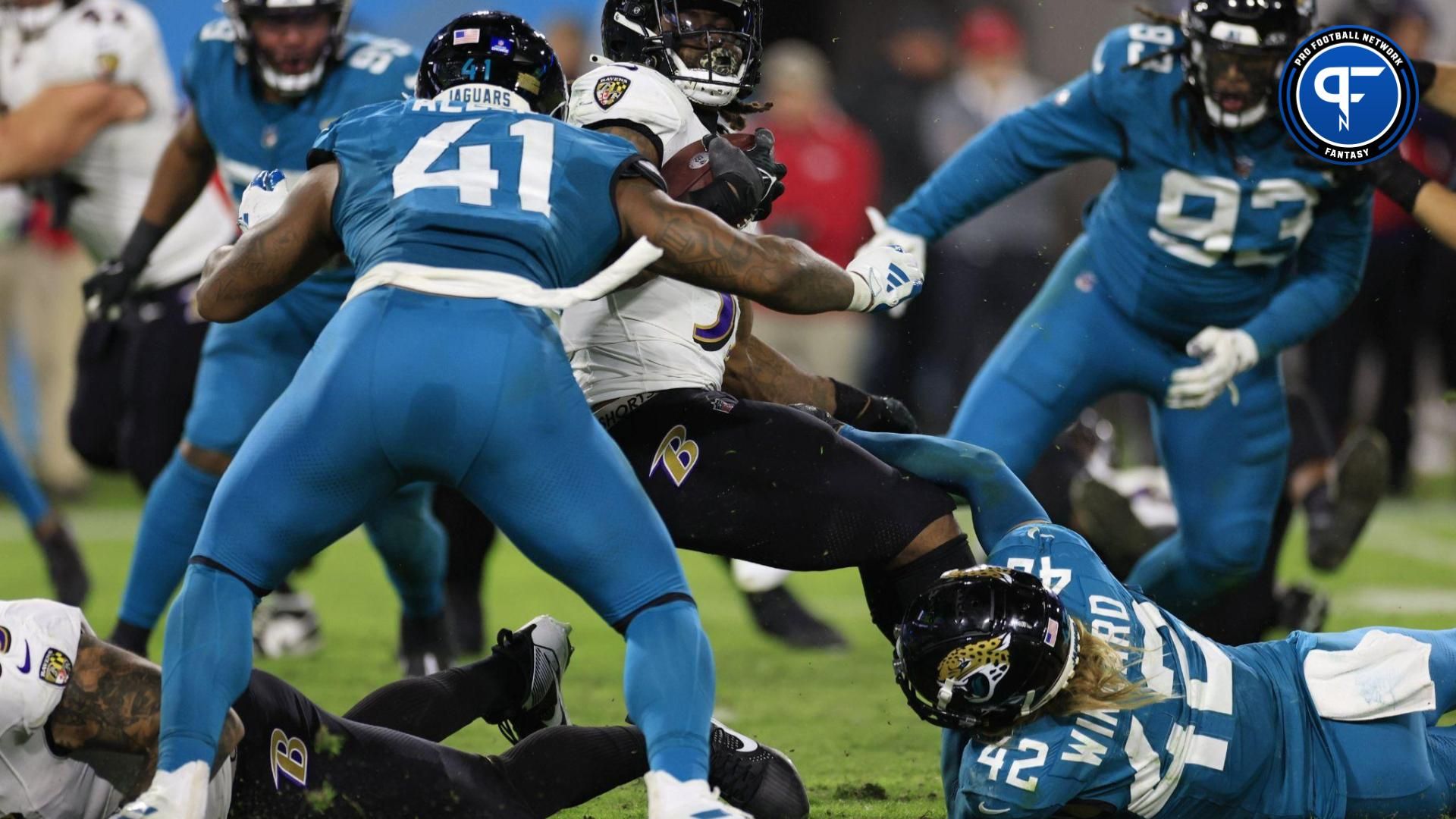 Baltimore Ravens running back Gus Edwards (35) rushes for yards as he is stopped by Jacksonville Jaguars linebacker Josh Allen (41) and safety Andrew Wingard (42) during the fourth quarter of a regular season NFL football matchup.