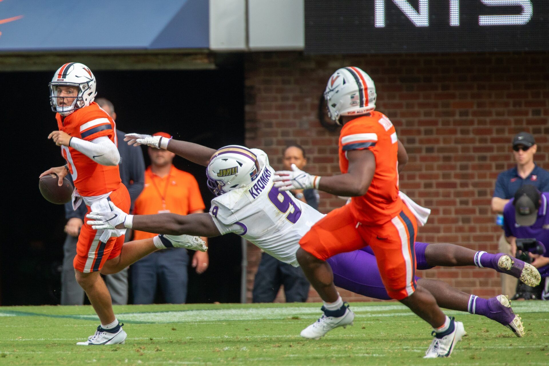 Virginia Cavaliers quarterback Anthony Colandrea (10) evades a tackle from James Madison Dukes defensive lineman Jamree Kromah (9) during the second half at Scott Stadium.