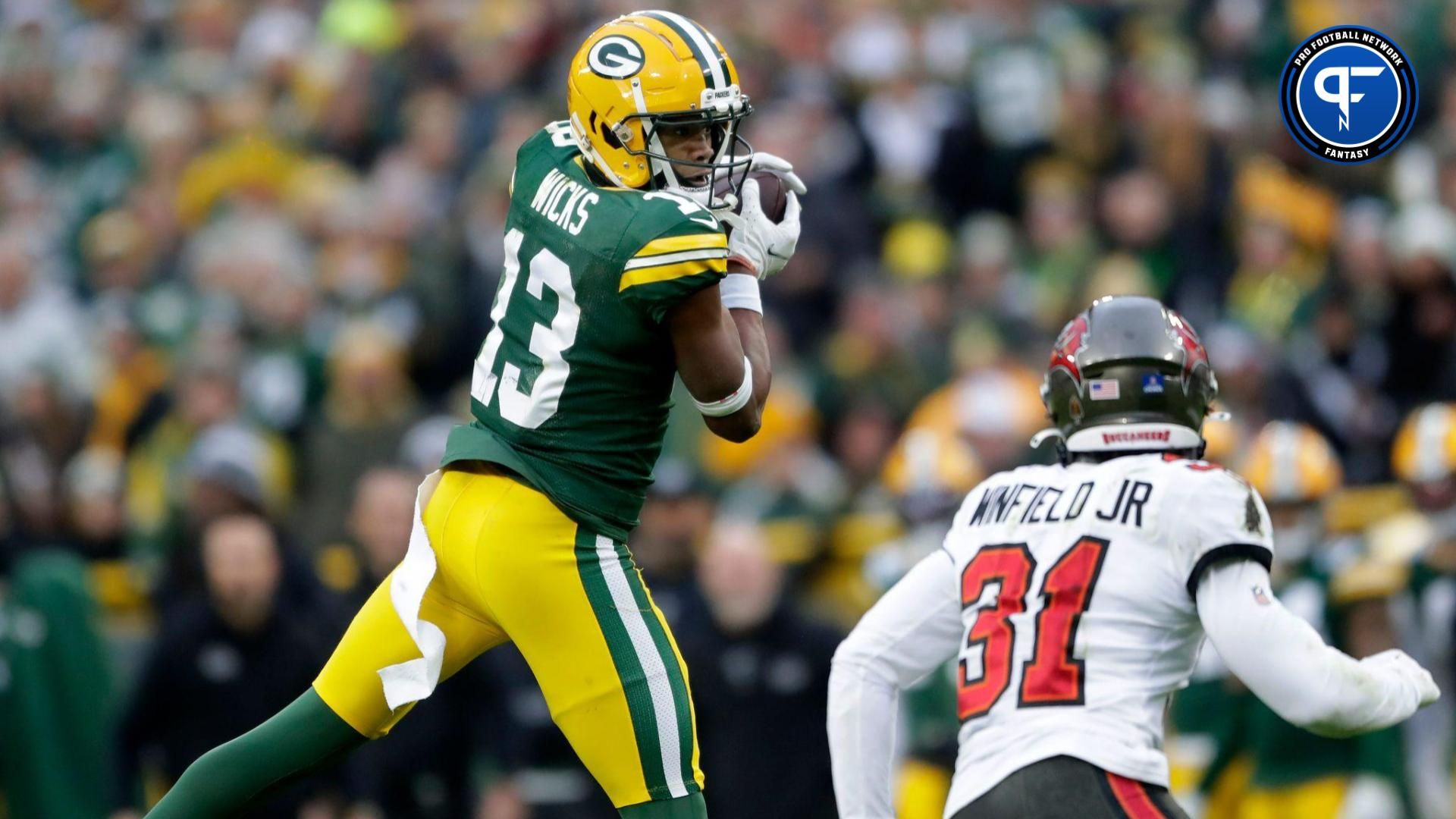 Green Bay Packers wide receiver Dontayvion Wicks (13) catches a pass in front of the defense of Tampa Bay Buccaneers safety Antoine Winfield Jr. (31) during their football game.