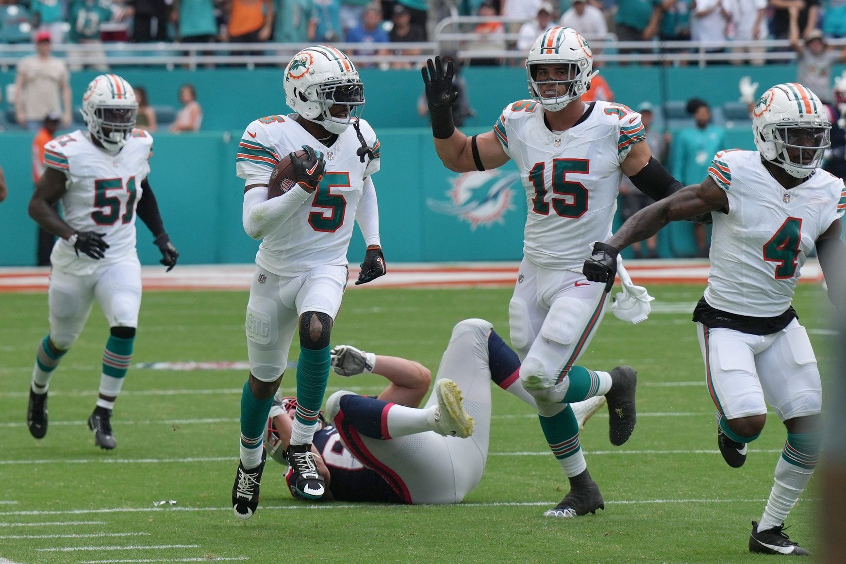 Miami Dolphins players celebrate after a Jalen Ramsey (5) interception against the New England Patriots.