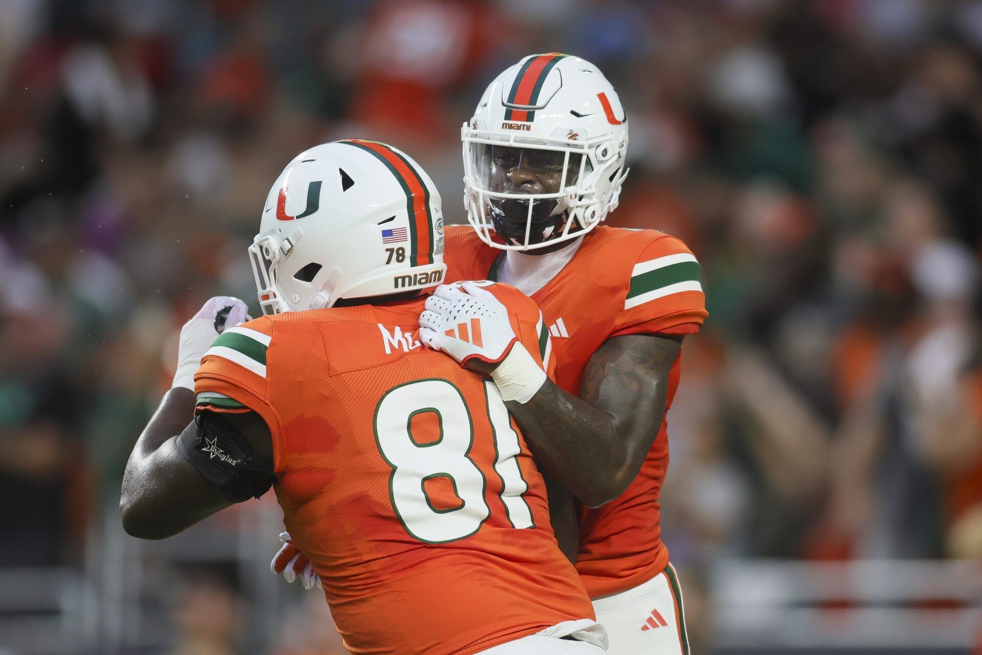 Colbie Young (4) celebrates with offensive lineman Francis Mauigoa (81) after scoring a touchdown against the Miami Redhawks during the first quarter at Hard Rock Stadium.