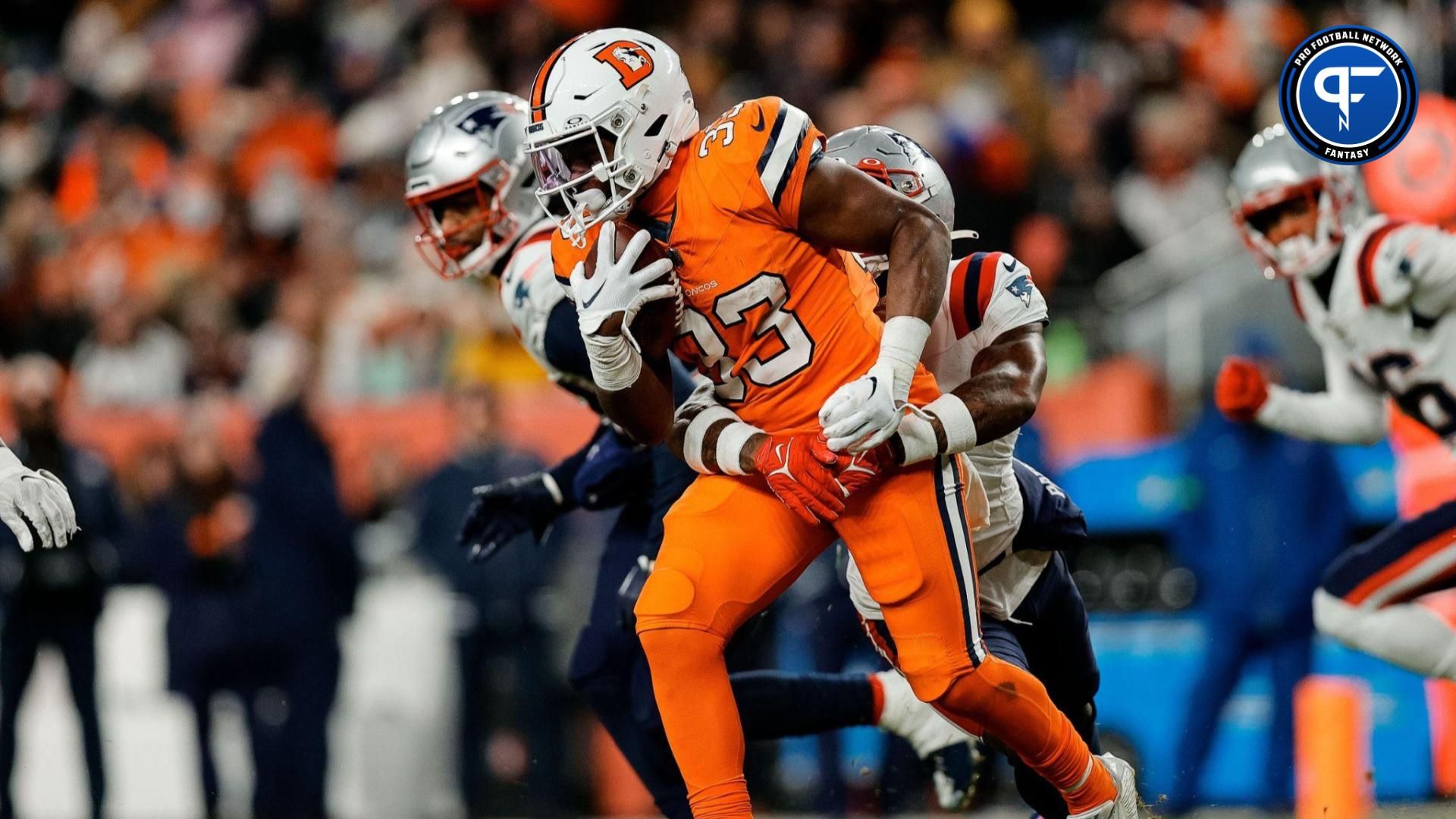 Denver Broncos running back Javonte Williams (33) runs the ball against New England Patriots cornerback Jalen Mills (2) in the second quarter at Empower Field at Mile High.