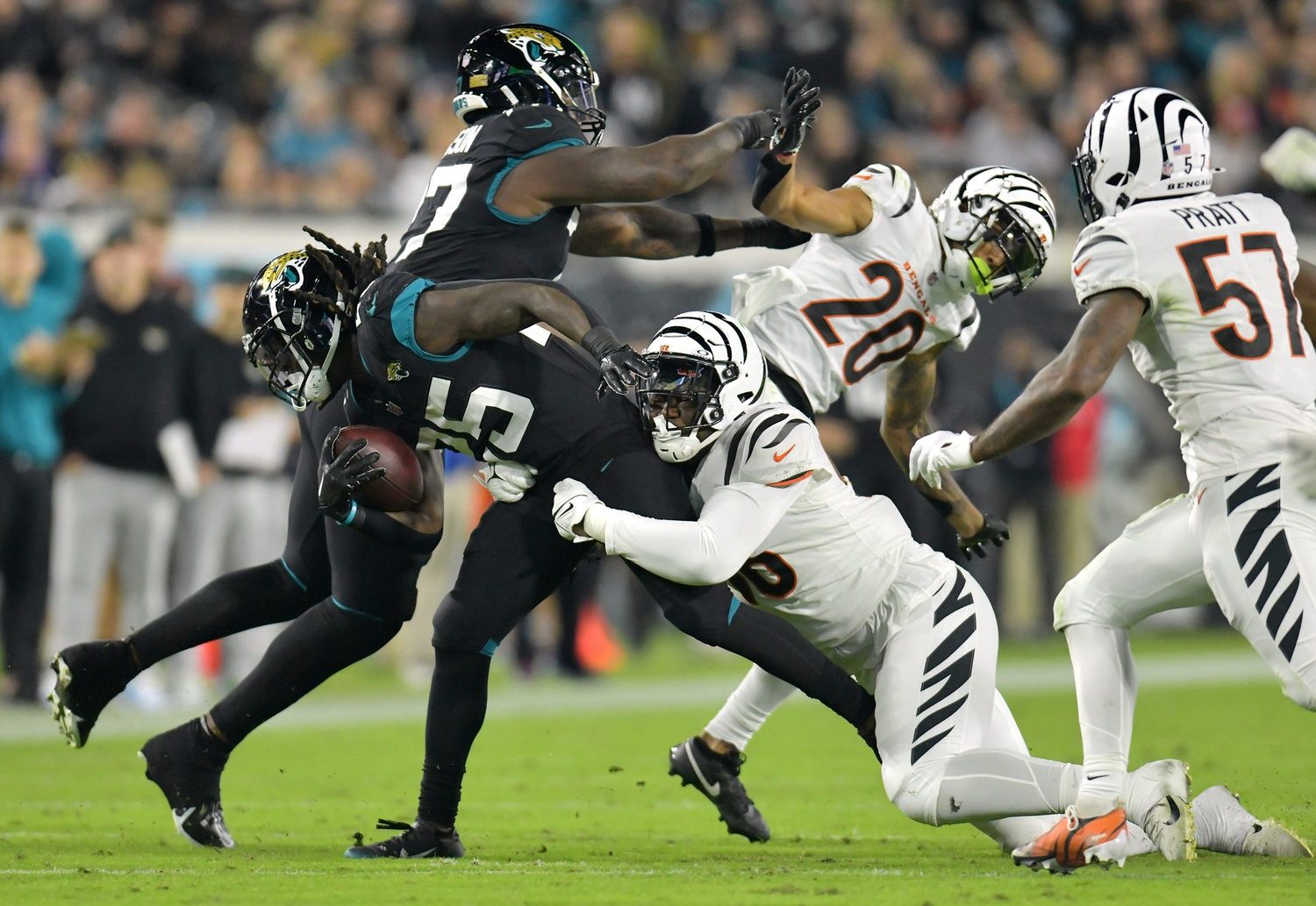 Jacksonville Jaguars offensive tackle Anton Harrison (77) pushes off Cincinnati Bengals cornerback DJ Turner II (20) as Jacksonville Jaguars running back D'Ernest Johnson (25) tries to shake Cincinnati Bengals defensive end Cam Sample (96).