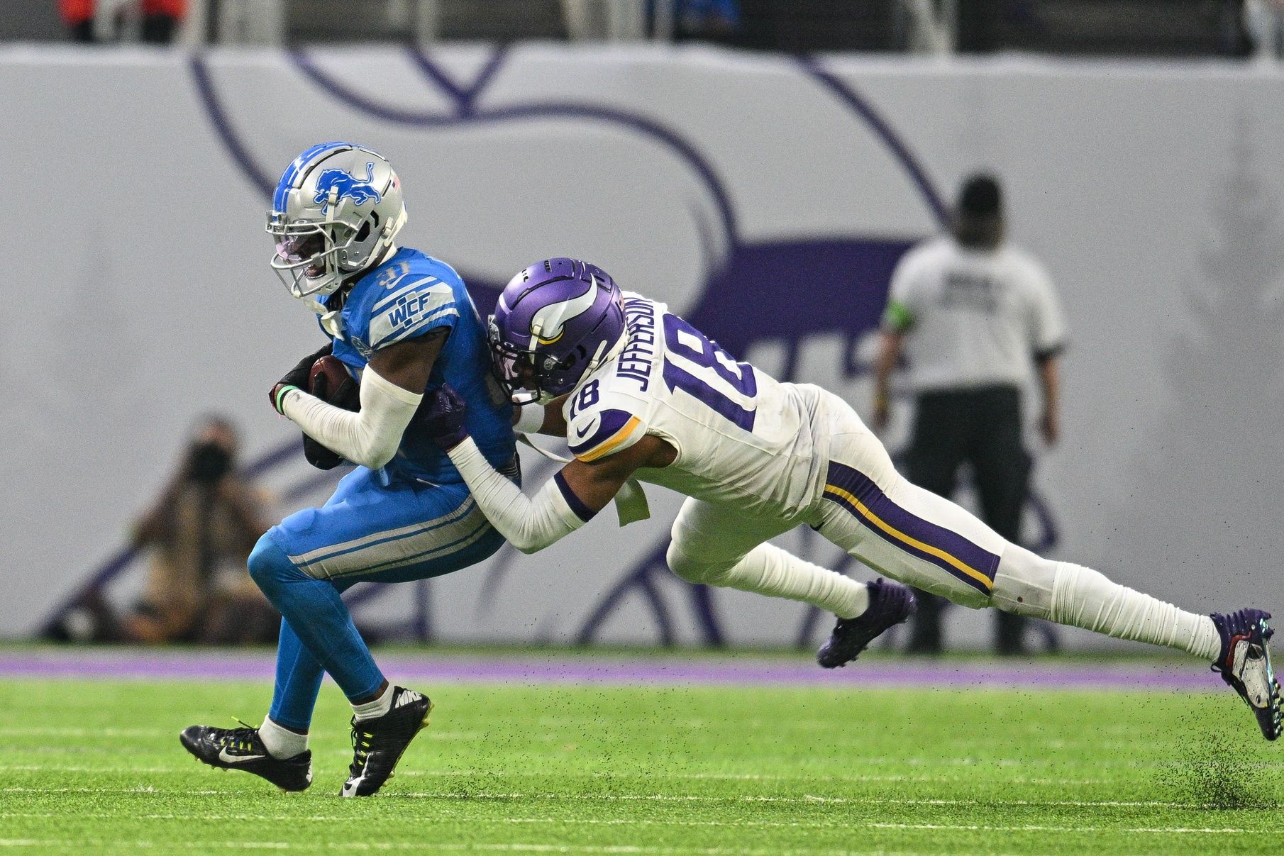 Detroit Lions S Kerby Joseph (31) makes an interception in front of Minnesota Vikings WR Justin Jefferson (18).