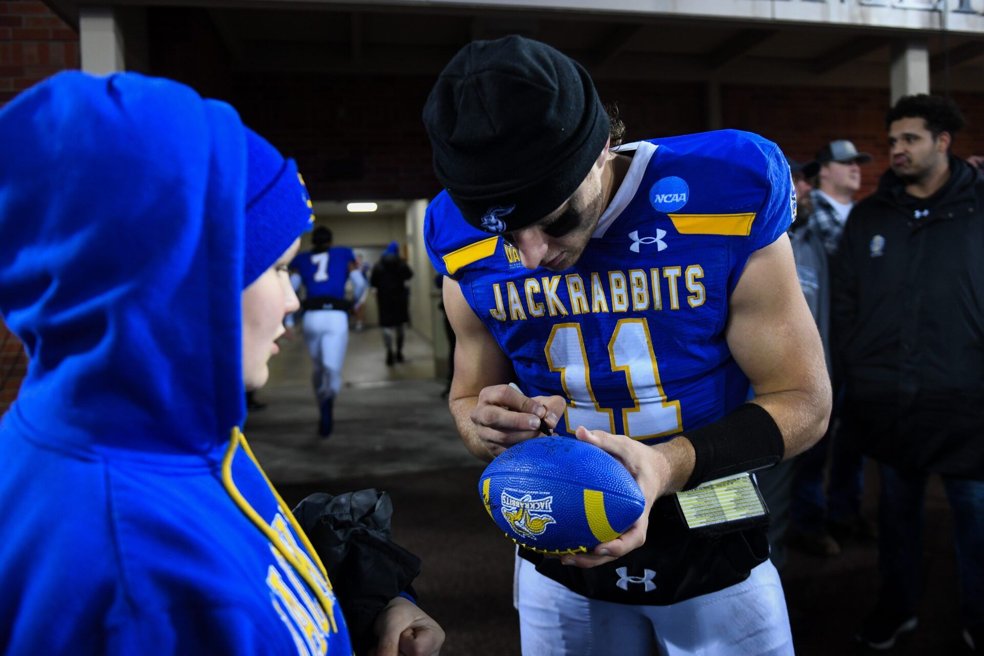 SDSU's quarterback Mark Gronowski (11) signs a football for a kid after winning the FCS semifinals