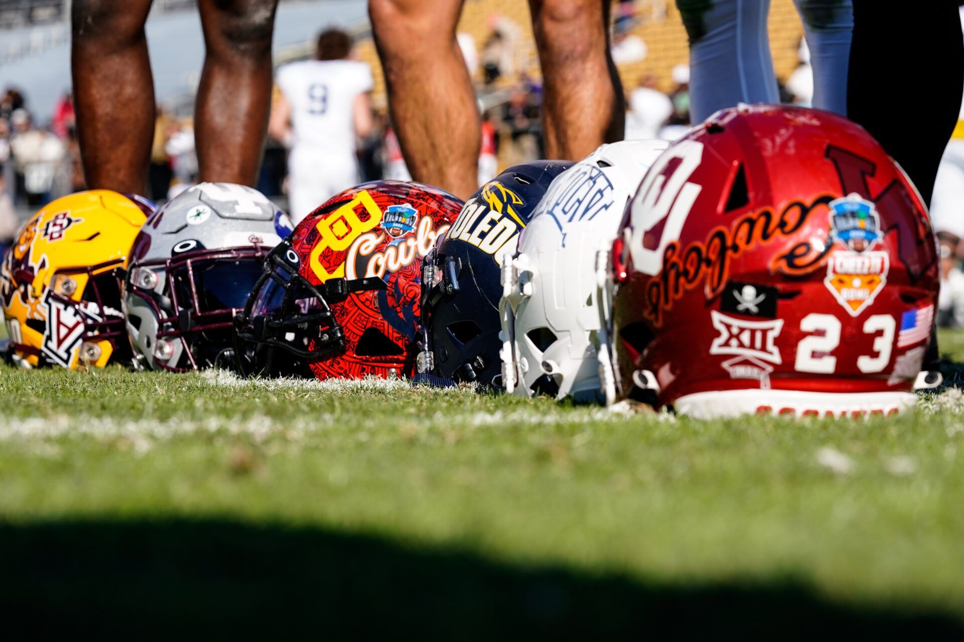 Team Kai and Team Aina players place their helmets on the ground to take a photo in the 2023 Hula Bowl at UCF FBC Mortgage Stadium.