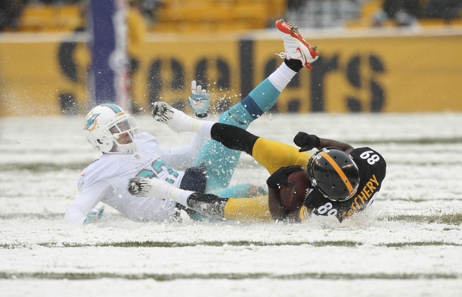 Pittsburgh Steelers wide receiver Jerricho Cotchery (89) and Miami Dolphins safety Jimmy Wilson (27) slide in the snow after the play is down during the first half at Heinz Field.