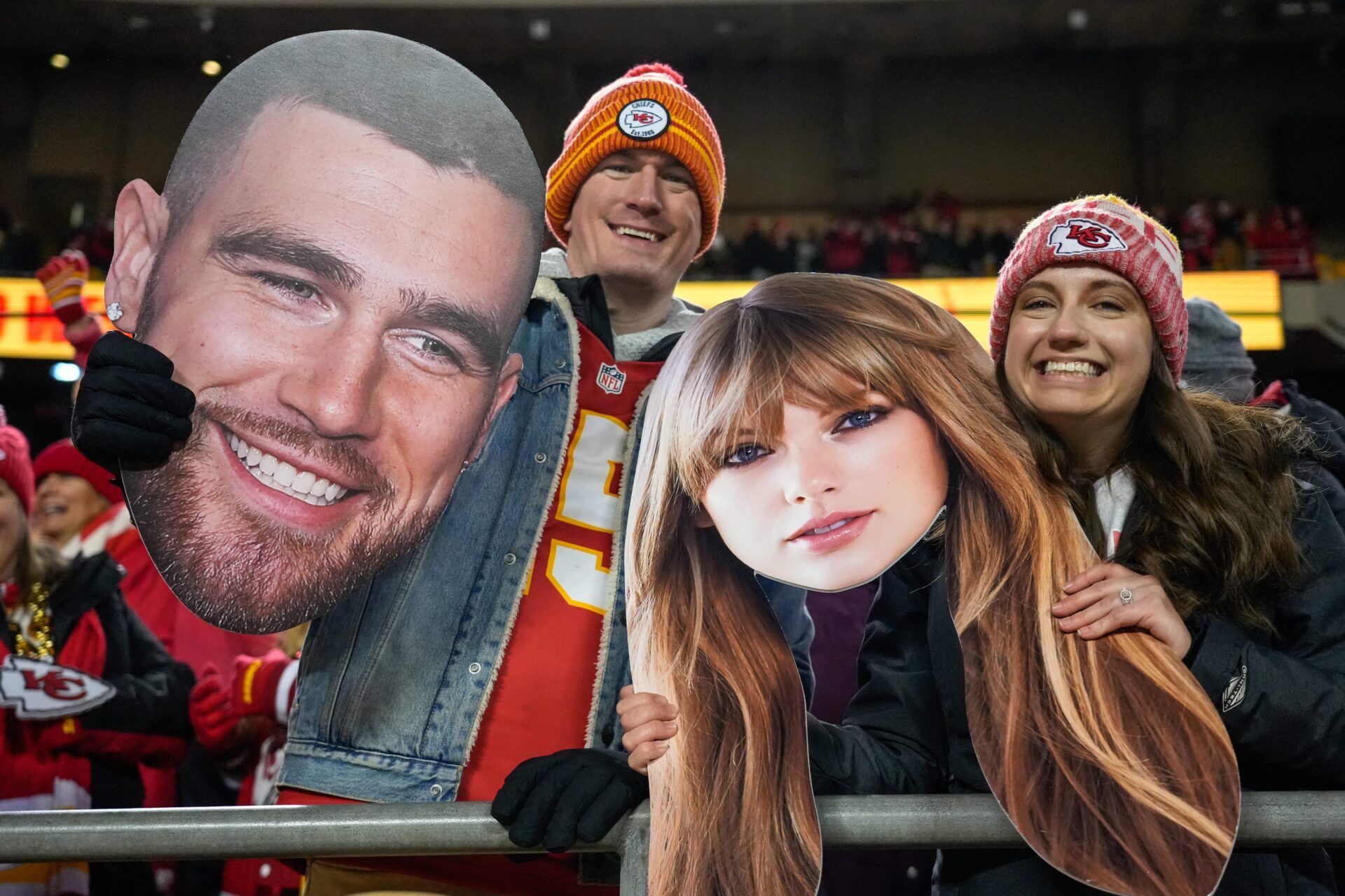 Fans wave big heads of Travis Kelce and Taylor Swift after the fourth quarter of the NFL Week 17 game between the Kansas City Chiefs and the Cincinnati Bengals at Arrowhead Stadium