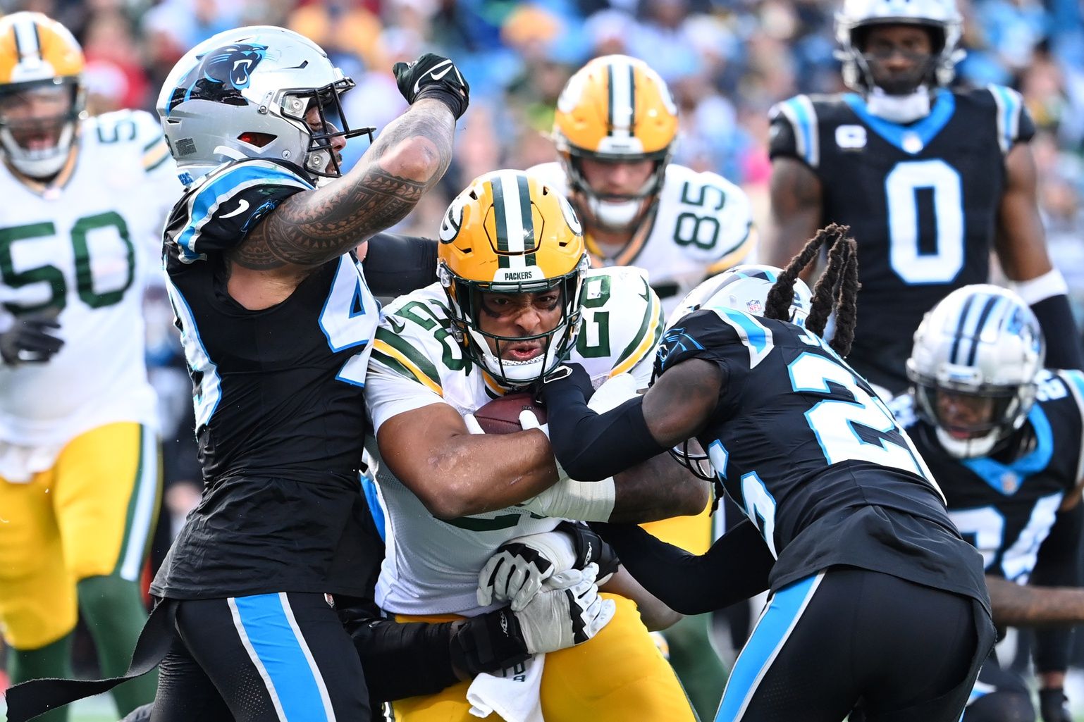 Green Bay Packers running back AJ Dillon (28) with the ball as Carolina Panthers linebacker Frankie Luvu (49) and cornerback Donte Jackson (26) defend in the third quarter at Bank of America Stadium.