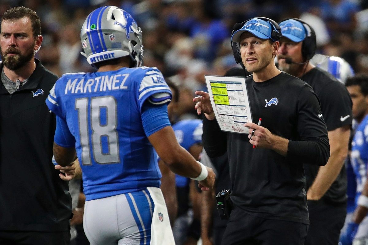 Detroit Lions QB Adrian Martinez (18) talks to offensive coordinator Ben Johnson during a preseason game.