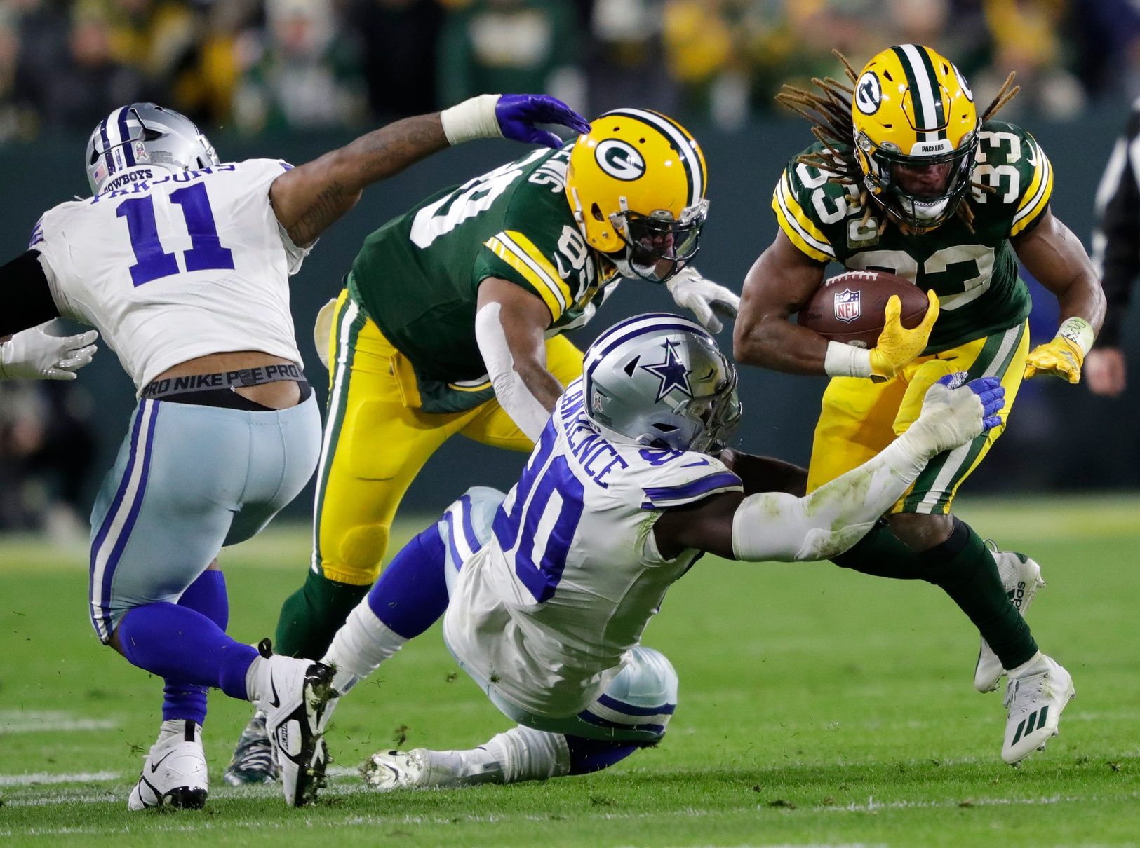 Green Bay Packers running back Aaron Jones (33) runs the ball against Dallas Cowboys defensive end DeMarcus Lawrence (90) during their football game Sunday, November 13, at Lambeau Field in Green Bay, Wis.