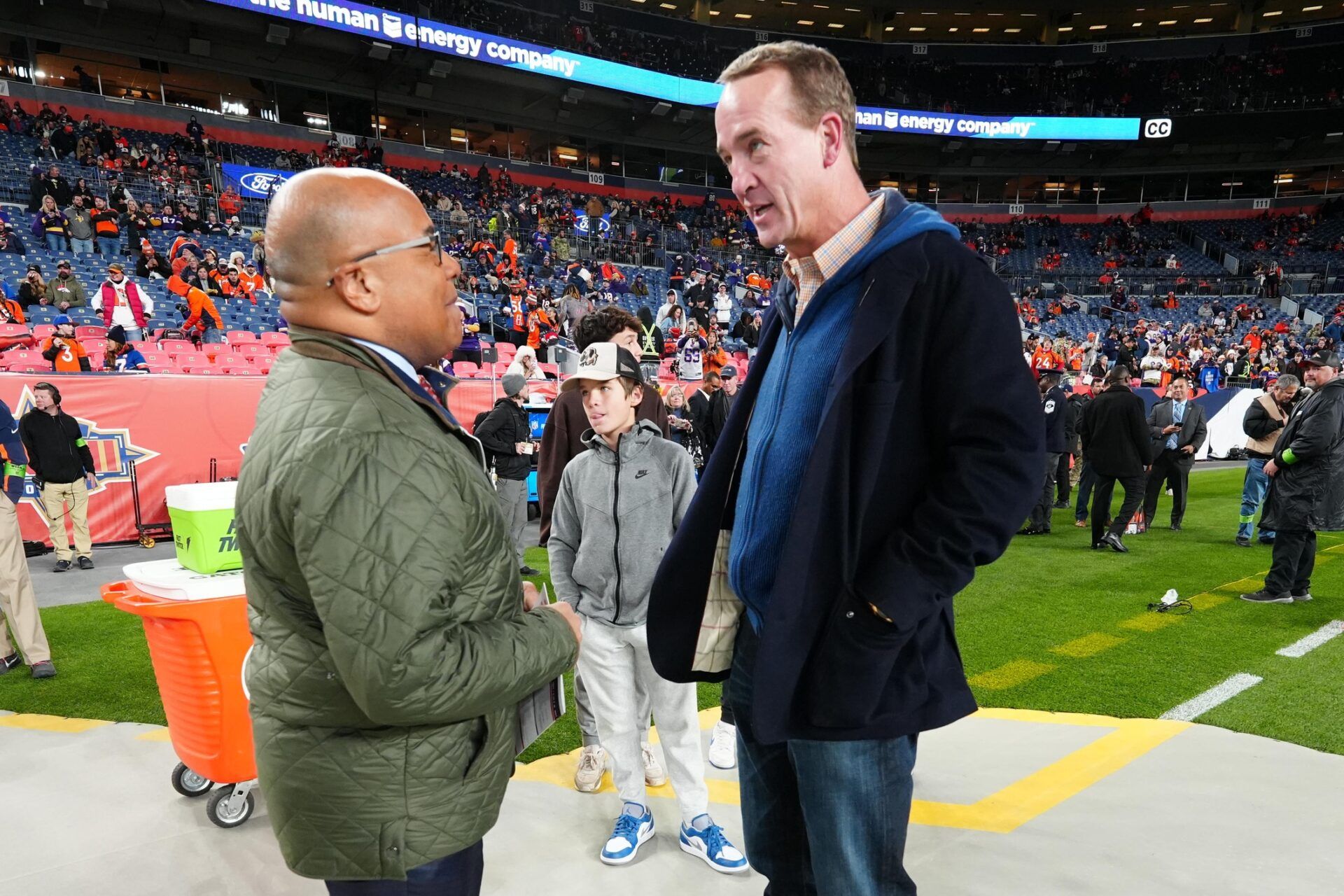 Hall of Fame QB Peyton Manning (right) and NFL analyst Mike Tirico (left) talk on the sidelines.