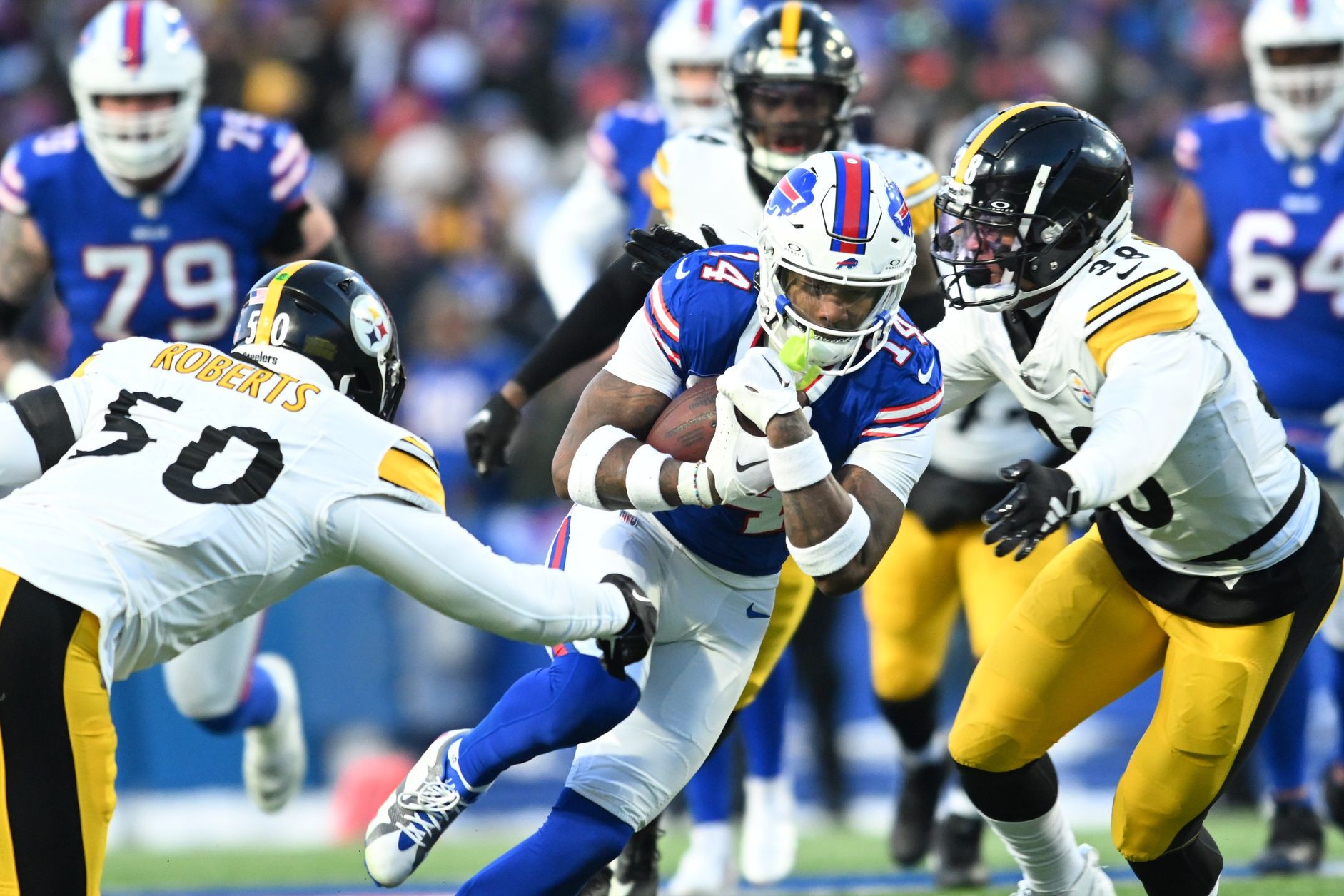 Buffalo Bills wide receiver Stefon Diggs (14) runs the ball pressured by Pittsburgh Steelers linebacker Elandon Roberts (50) and linebacker Mykal Walker (38) in the first half in a 2024 AFC wild card game at Highmark Stadium.