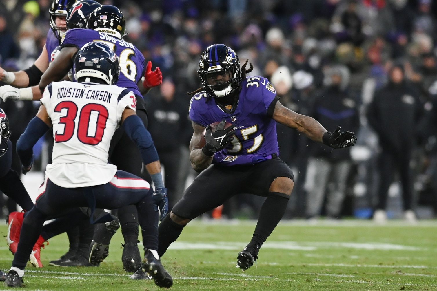 Baltimore Ravens running back Gus Edwards (35) runs the ball against Houston Texans safety DeAndre Houston-Carson (30) during the second quarter in a 2024 AFC divisional round game at M&T Bank Stadium.