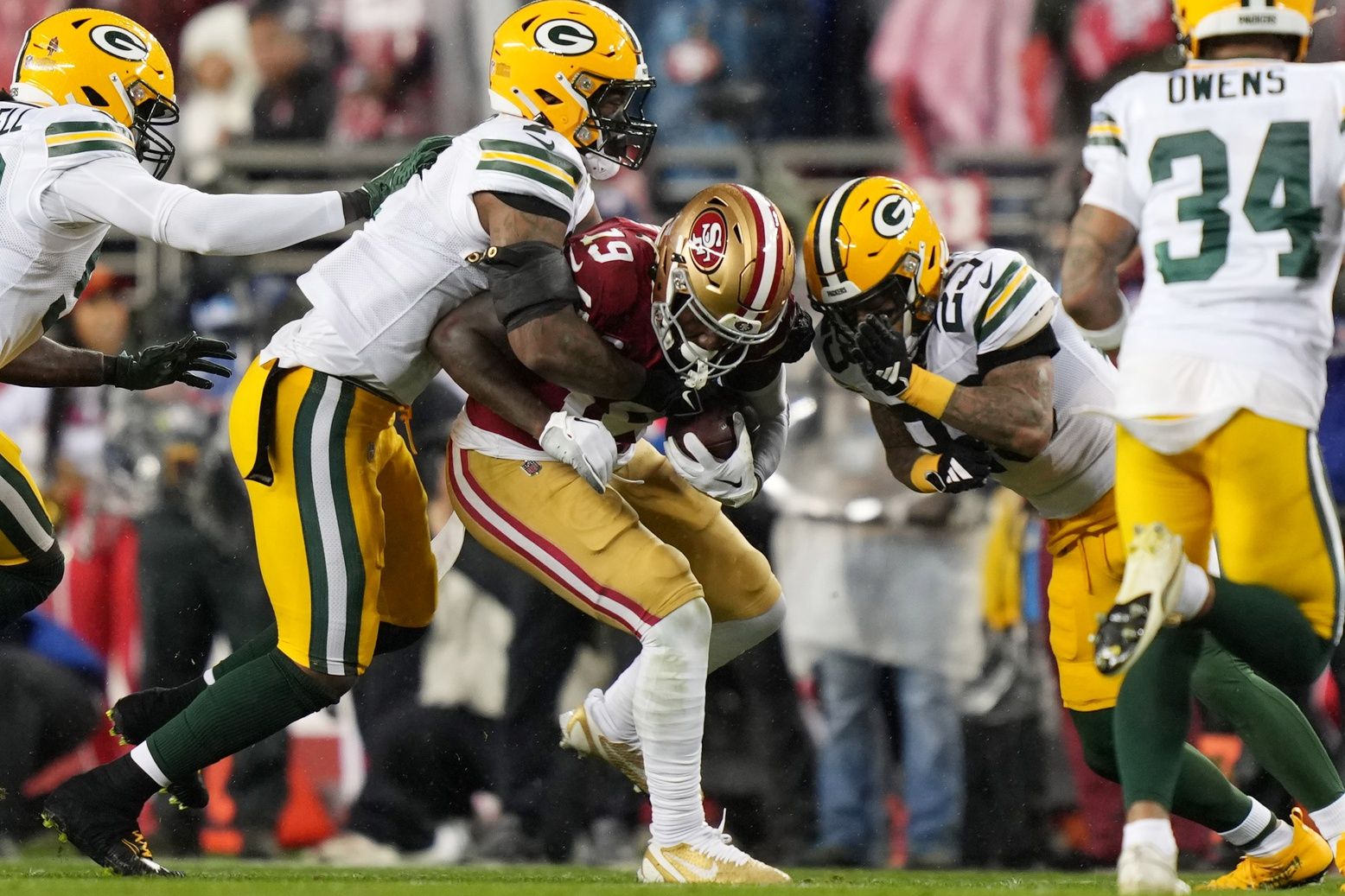 Green Bay Packers linebacker De'Vondre Campbell (59) and linebacker Quay Walker (7) and cornerback Jaire Alexander (23) tackle San Francisco 49ers wide receiver Deebo Samuel (19) in the during the second quarter in a 2024 NFC divisional round game at Levi's Stadium.