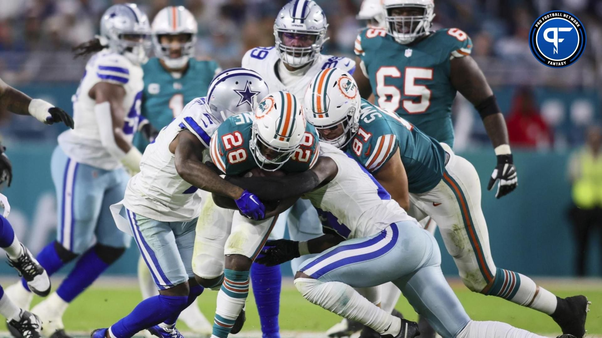 Miami Dolphins running back De'Von Achane (28) runs with the football against Dallas Cowboys cornerback Jourdan Lewis (2) and safety Markquese Bell (14) during the second quarter at Hard Rock Stadium.